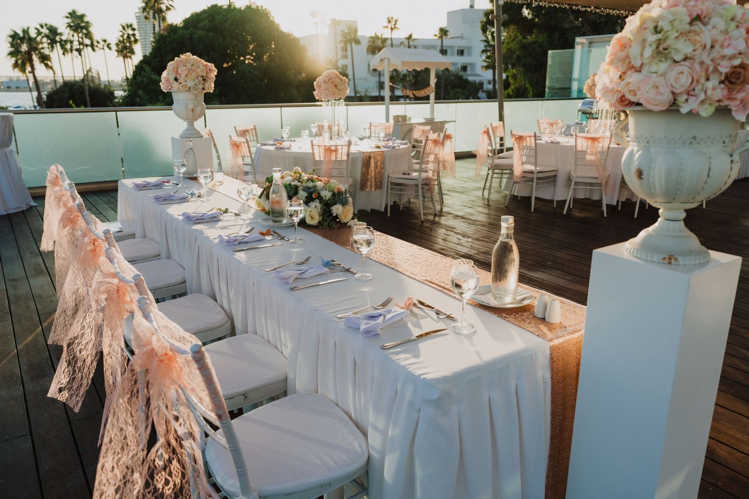 Outdoor wedding reception setup with white tables and peach floral decorations.