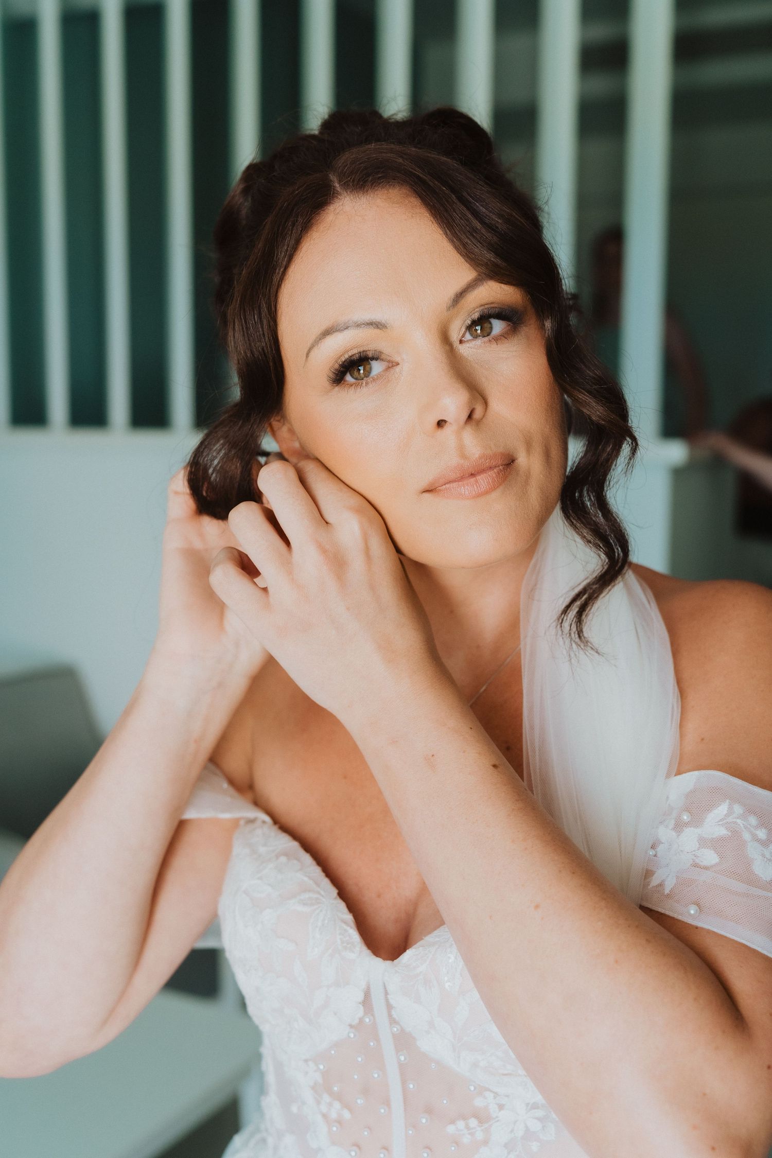 Ethereal bridal portrait features romantic makeup and hairstyling with a delicate white lace bodice in soft lighting.