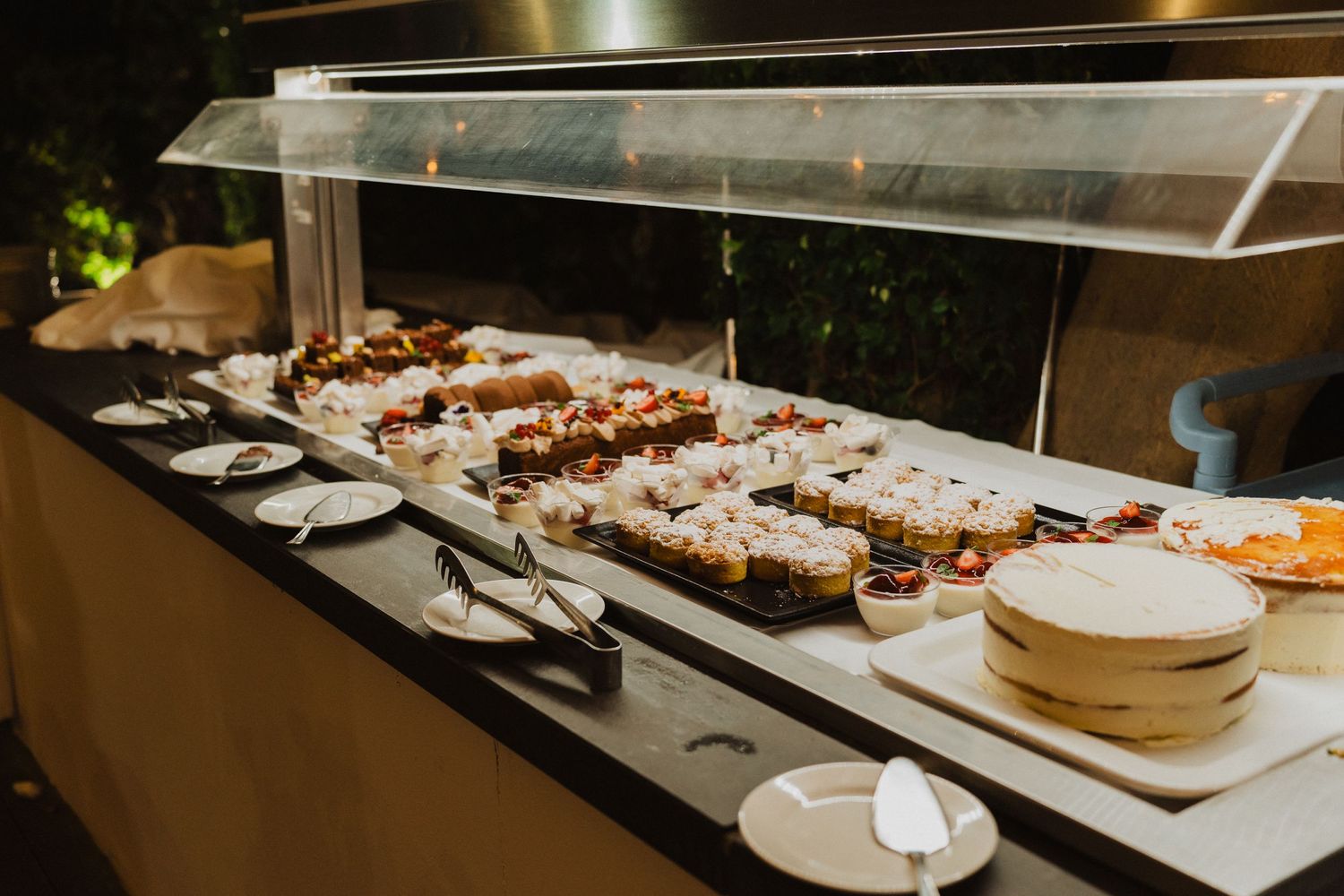 A catering buffet table displays appetizers and dishes behind a glass partition at an event.
