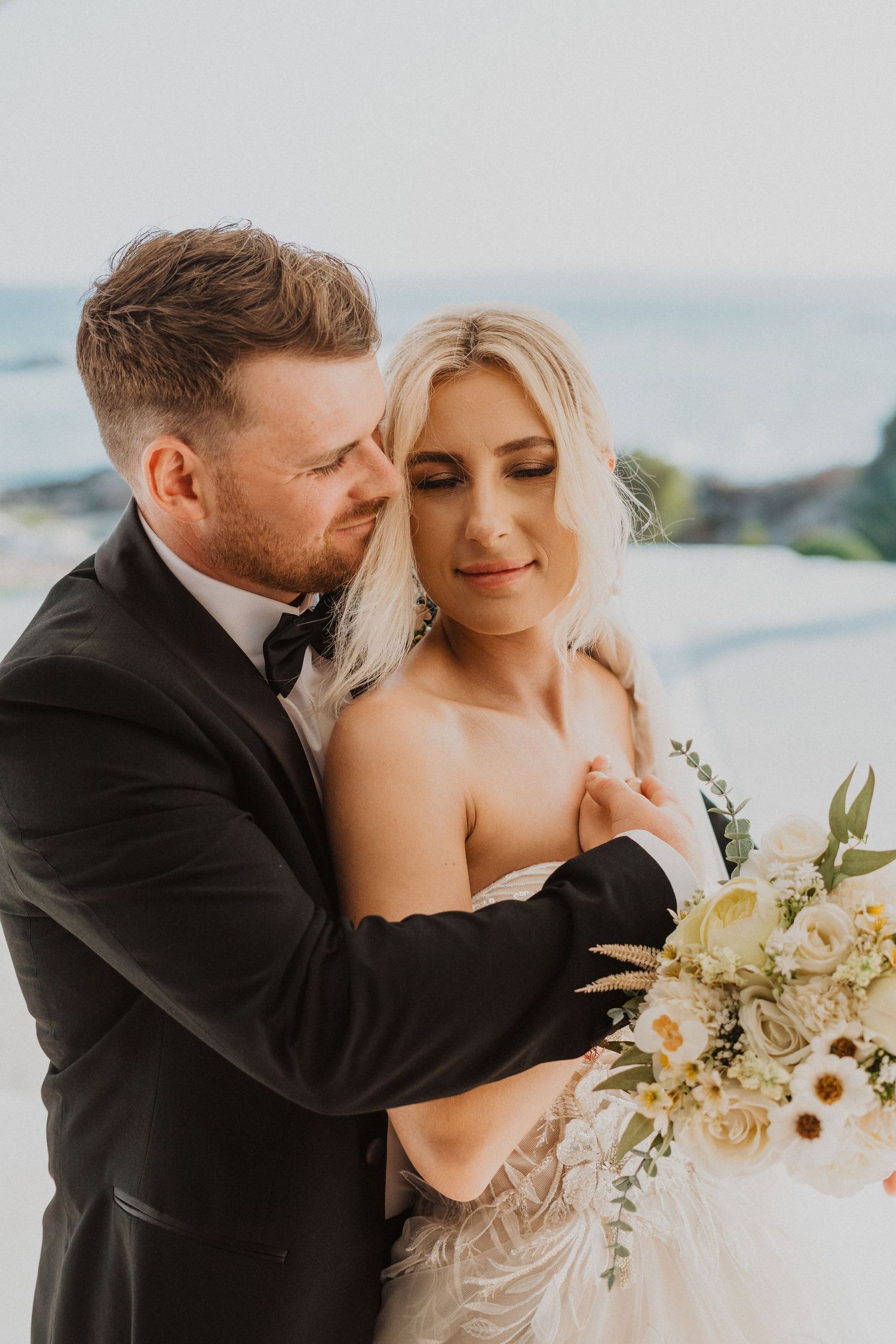 Intimate seaside wedding portrait with elegant white floral bouquet.