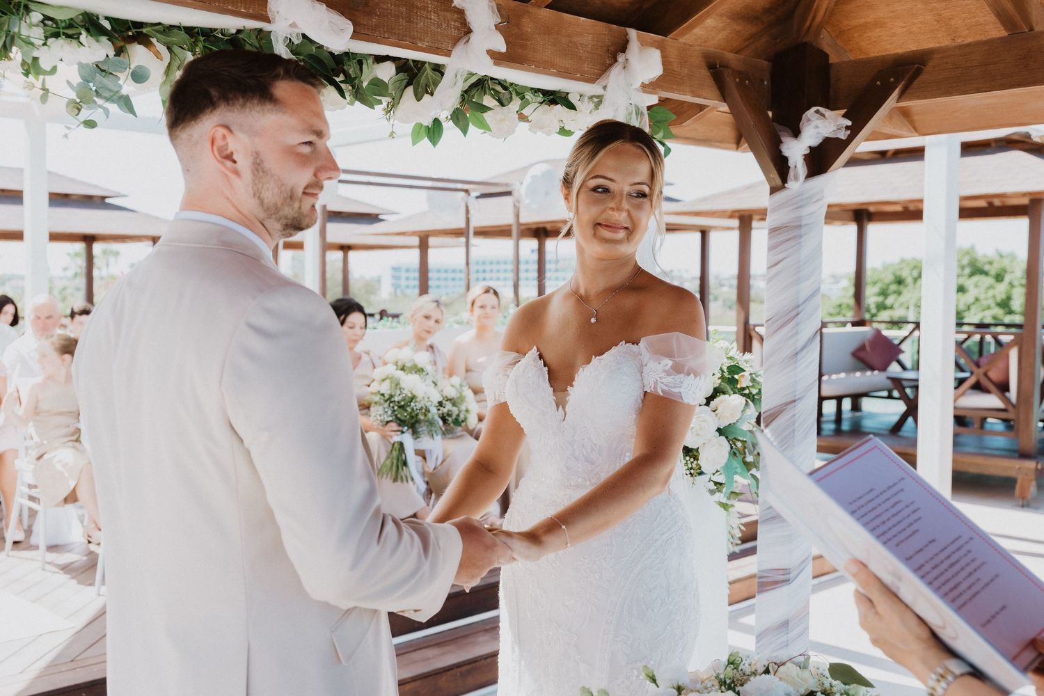 A couple shares an intimate moment during their wedding ceremony under a wooden pavilion.