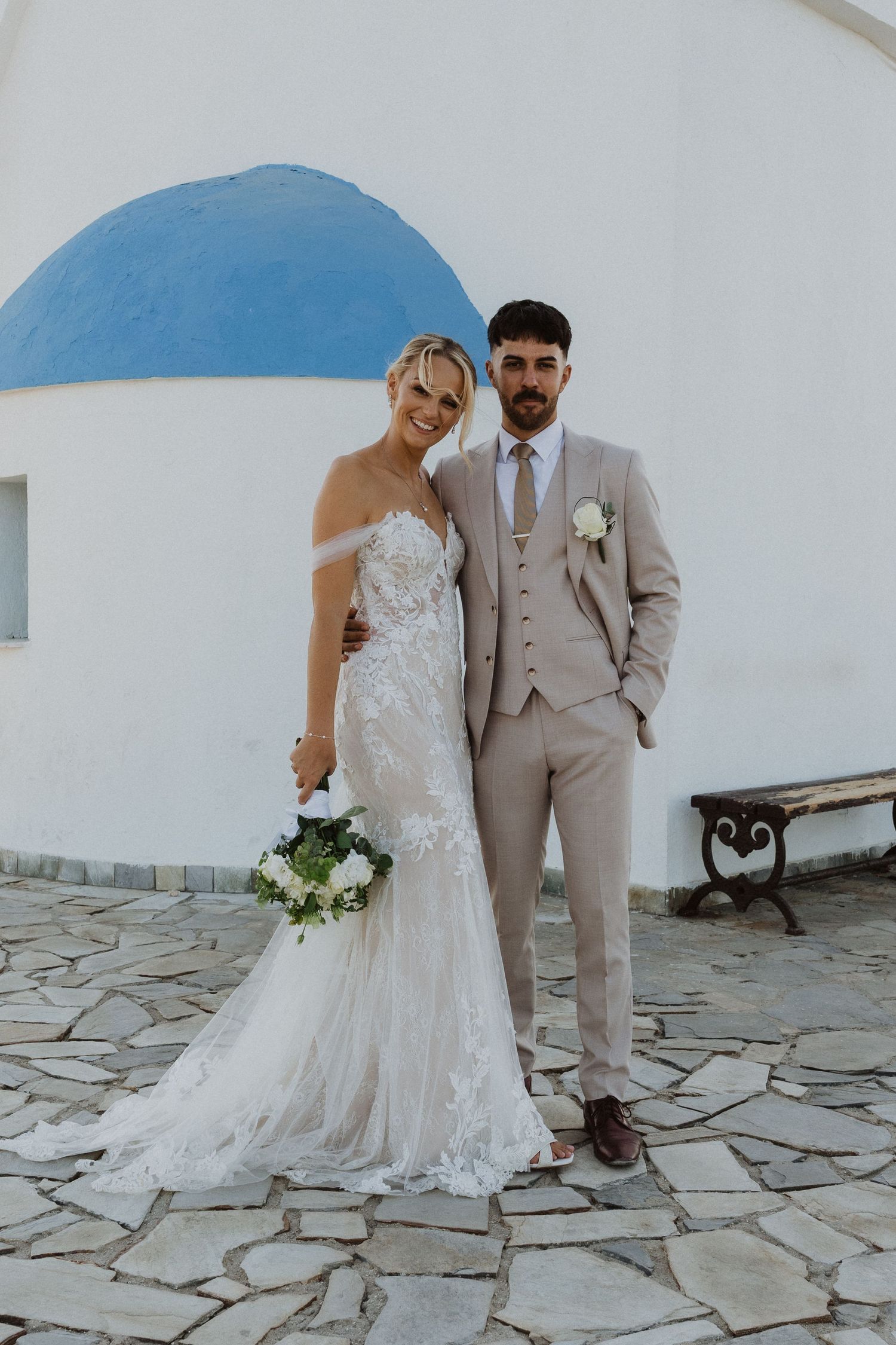 Wedding portraits at Greek church with classic white architecture and stone pathway.