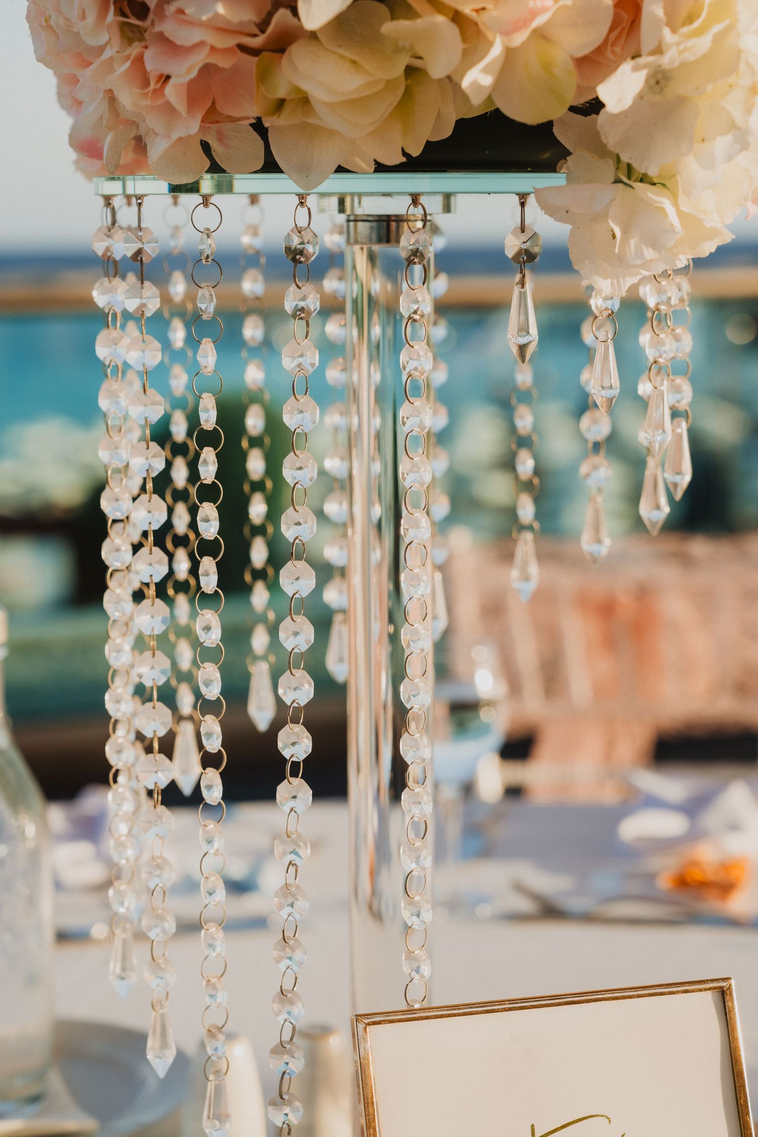 Crystal chandelier decorations with hanging beads and pink flowers for wedding table centerpiece.