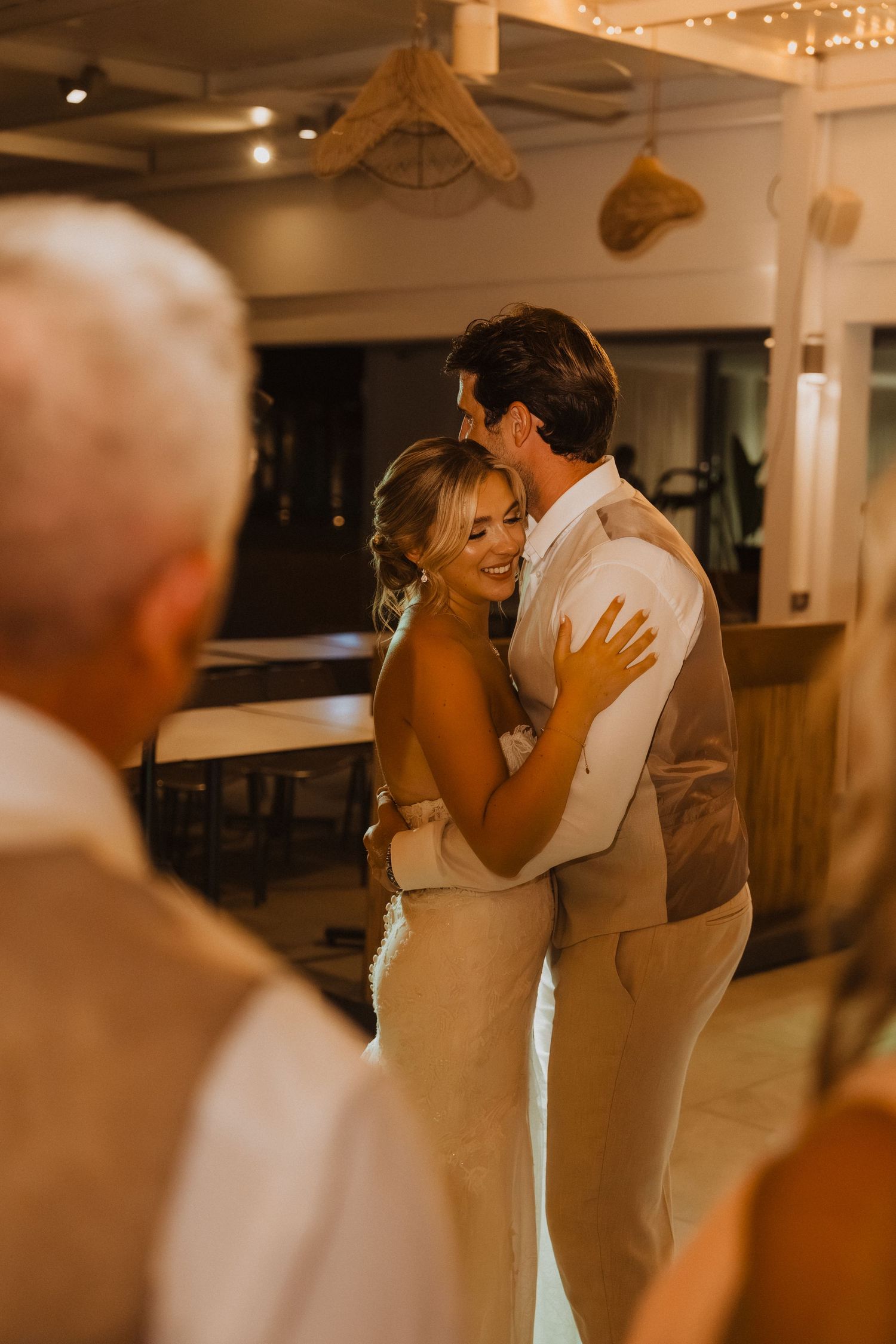 Intimate dance moment captured during wedding reception under warm lighting.
