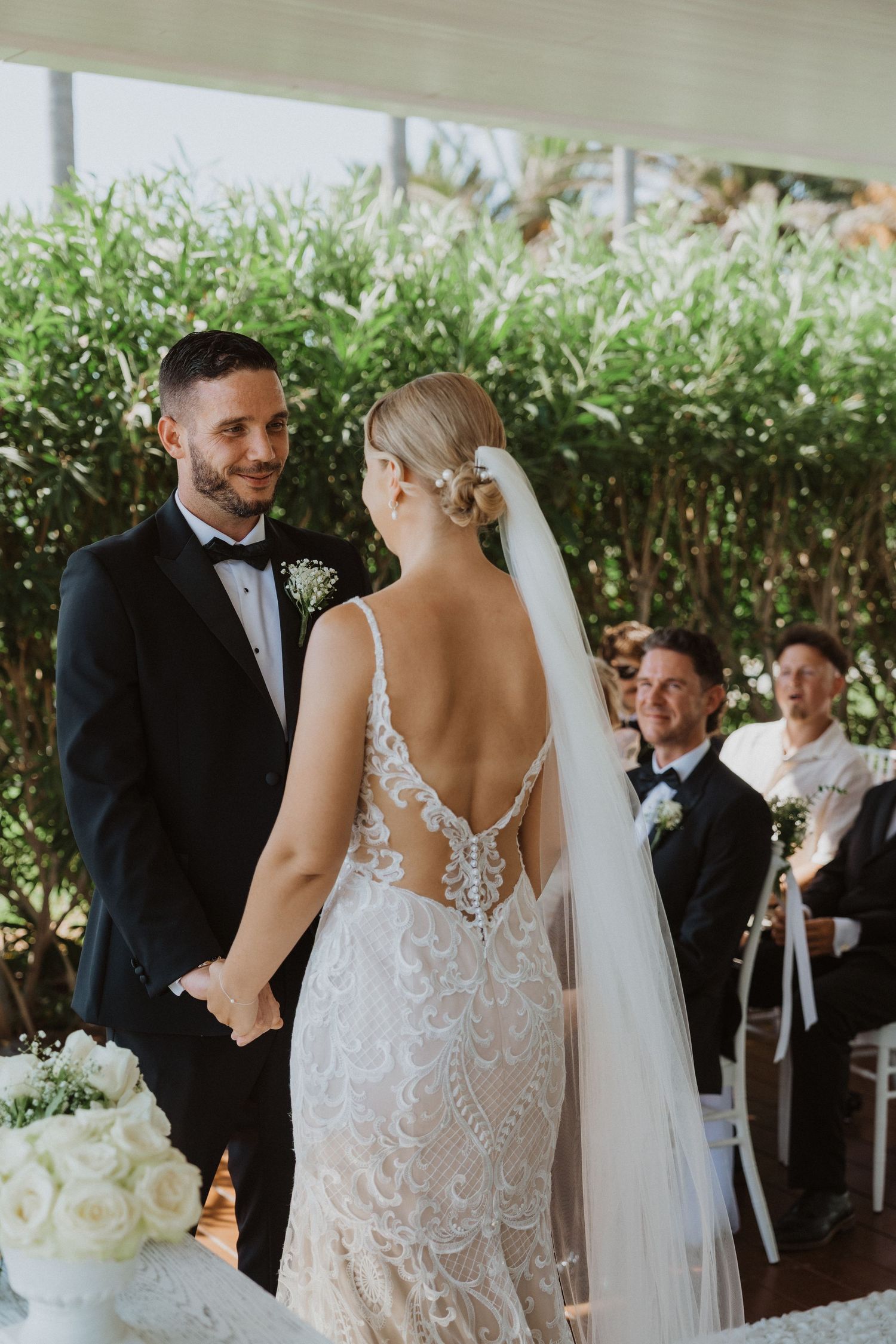 Romantic wedding ceremony moments captured under a covered outdoor venue with greenery backdrop.