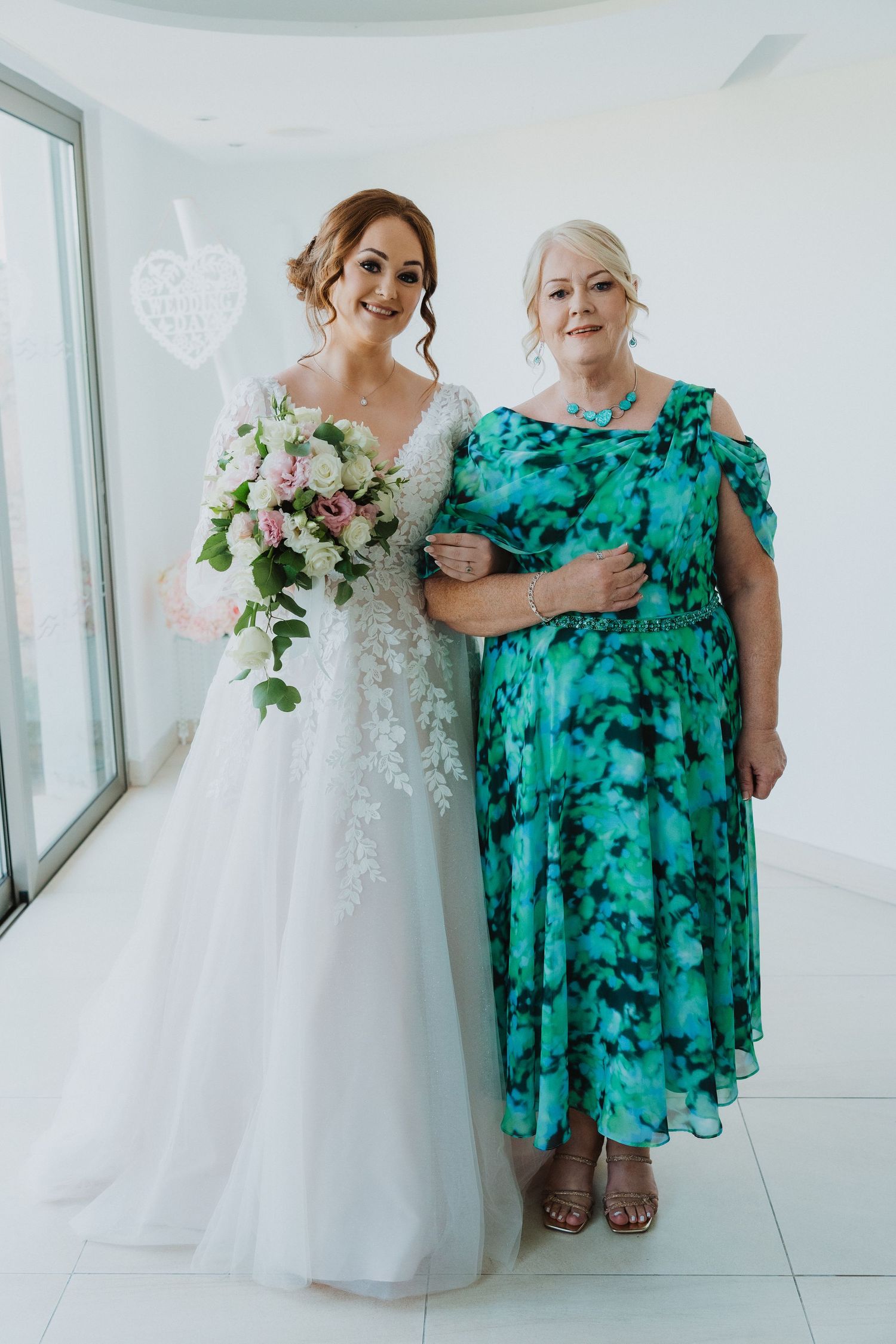 Wedding day portrait in a bright white room with elegant bridal attire.
