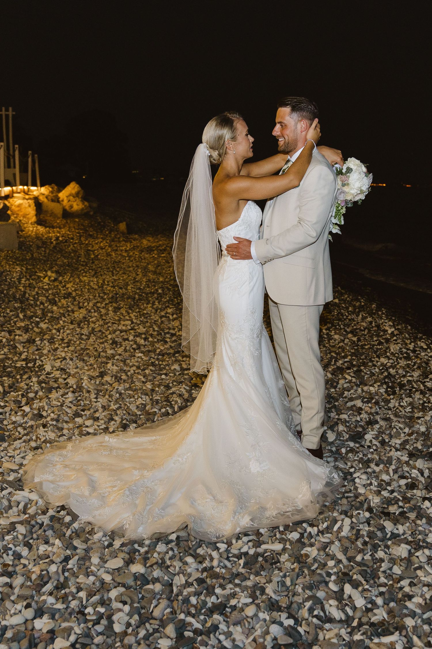 A stunning mermaid wedding dress with long train photographed during nighttime beach portraits.