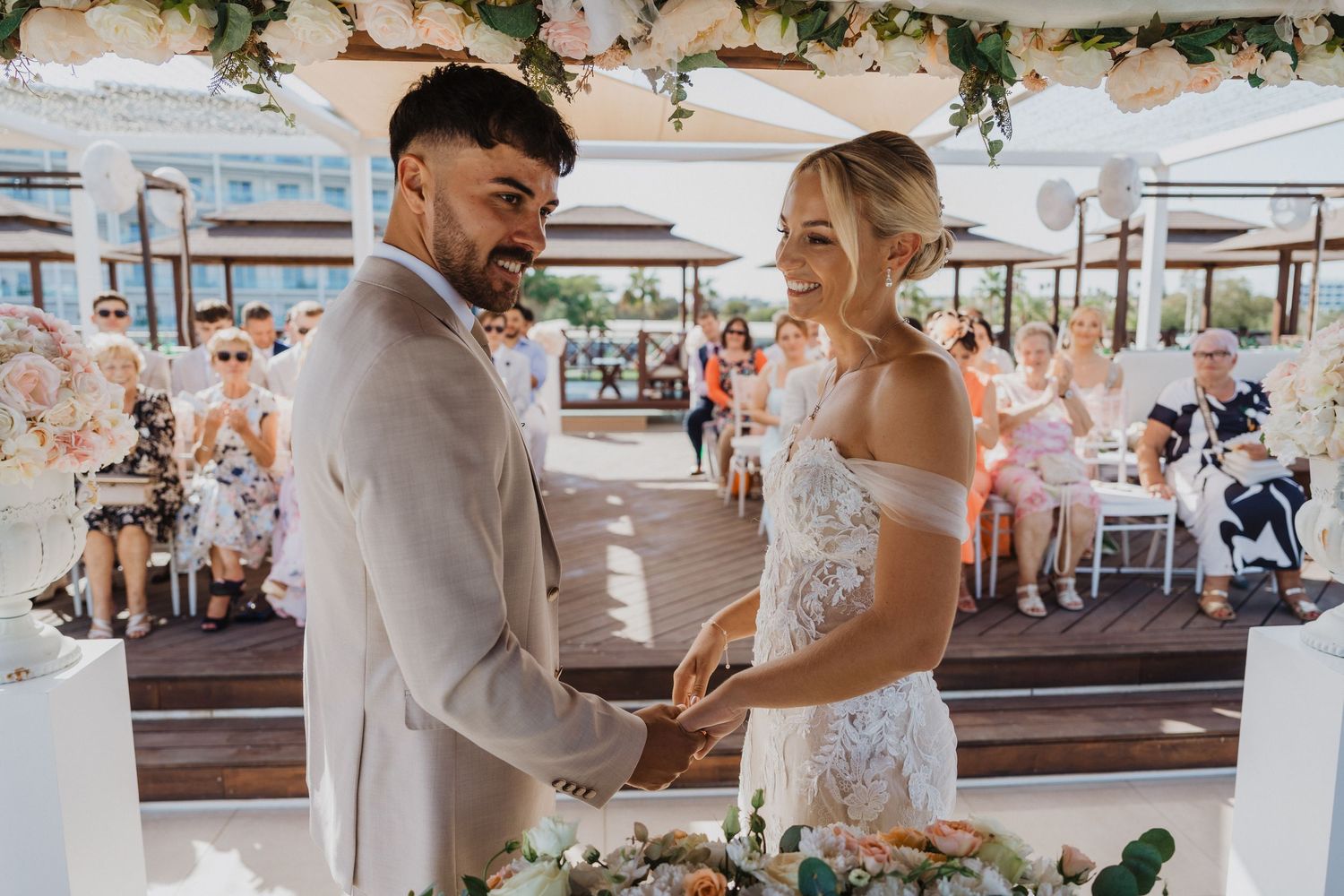 Wedding couple shares intimate moments during their seaside ceremony with elegant floral decorations.