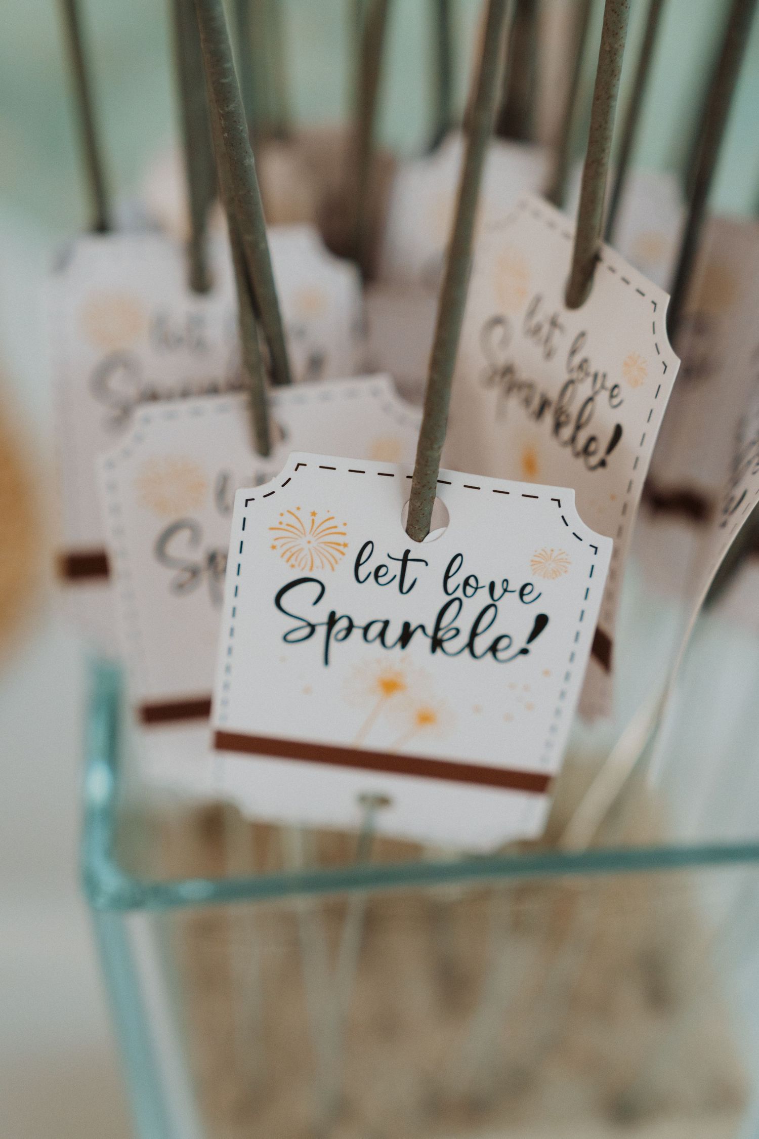 Delicate wedding favor tags with romantic messages hanging from strings in soft focus.