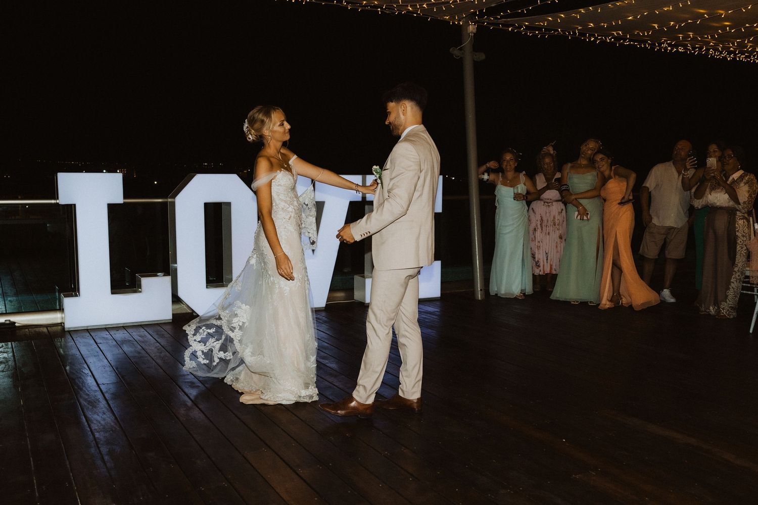 Couple sharing romantic dance moment by LOVE sign at wedding reception.