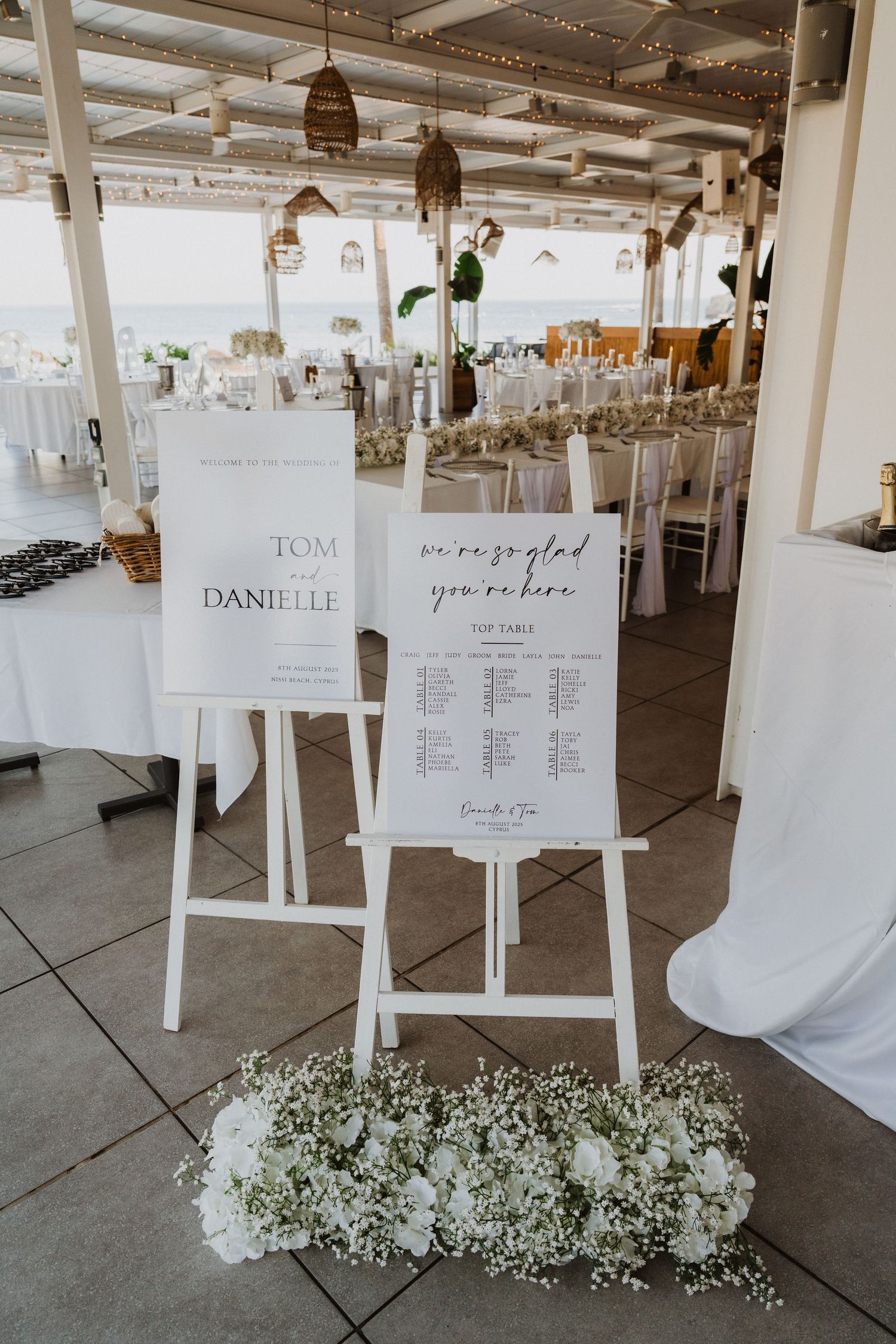 Wedding seating chart displays with white frames and floral decorations in a reception venue.