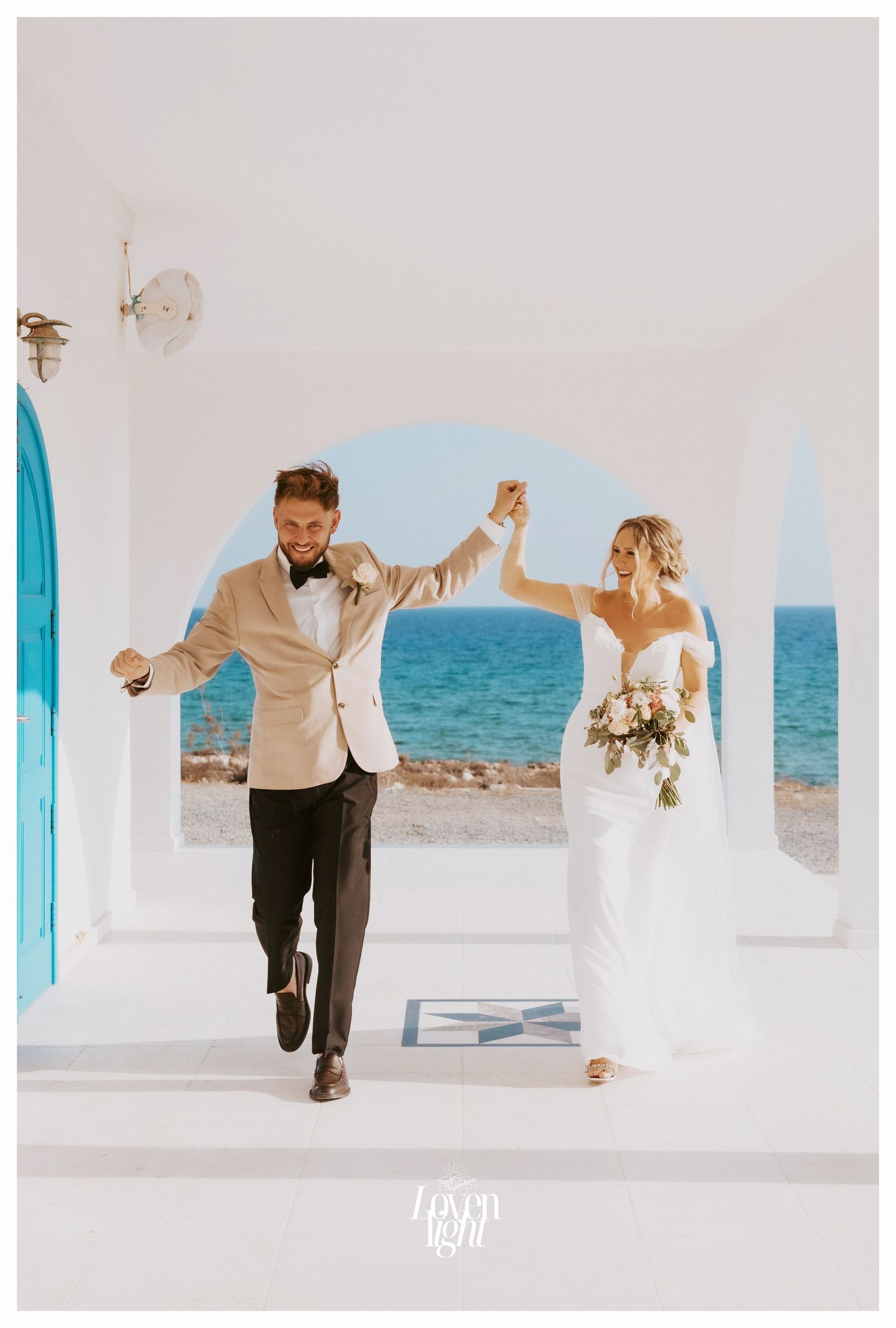 Celebratory wedding moment with couple dancing under white coastal archway.