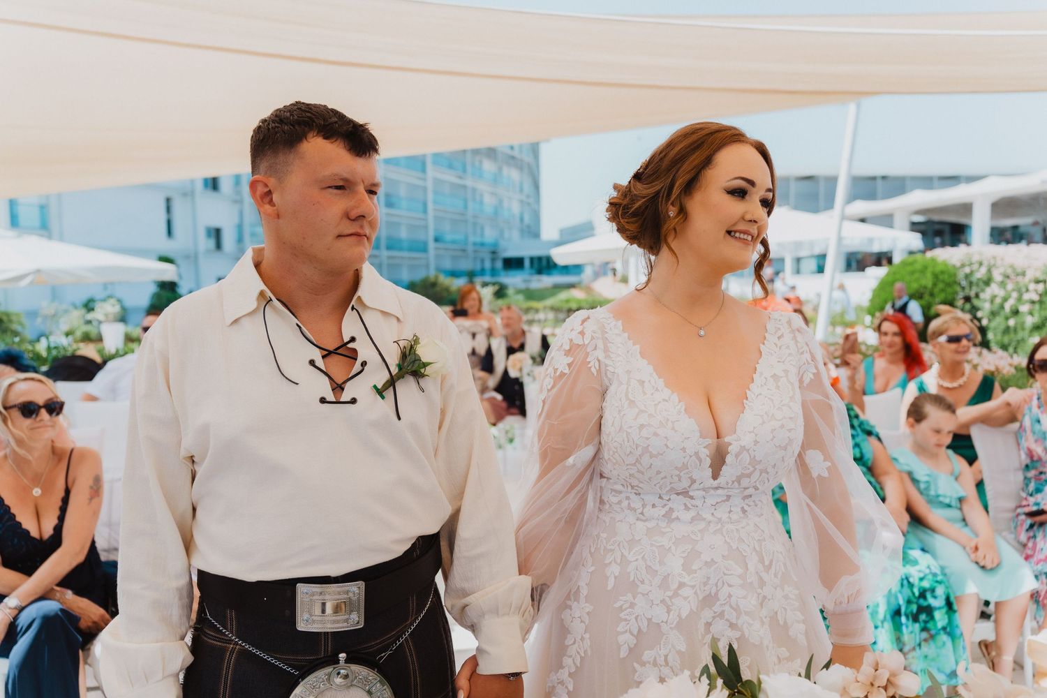Newlyweds share a joyful moment during their beach wedding with guests in attendance.