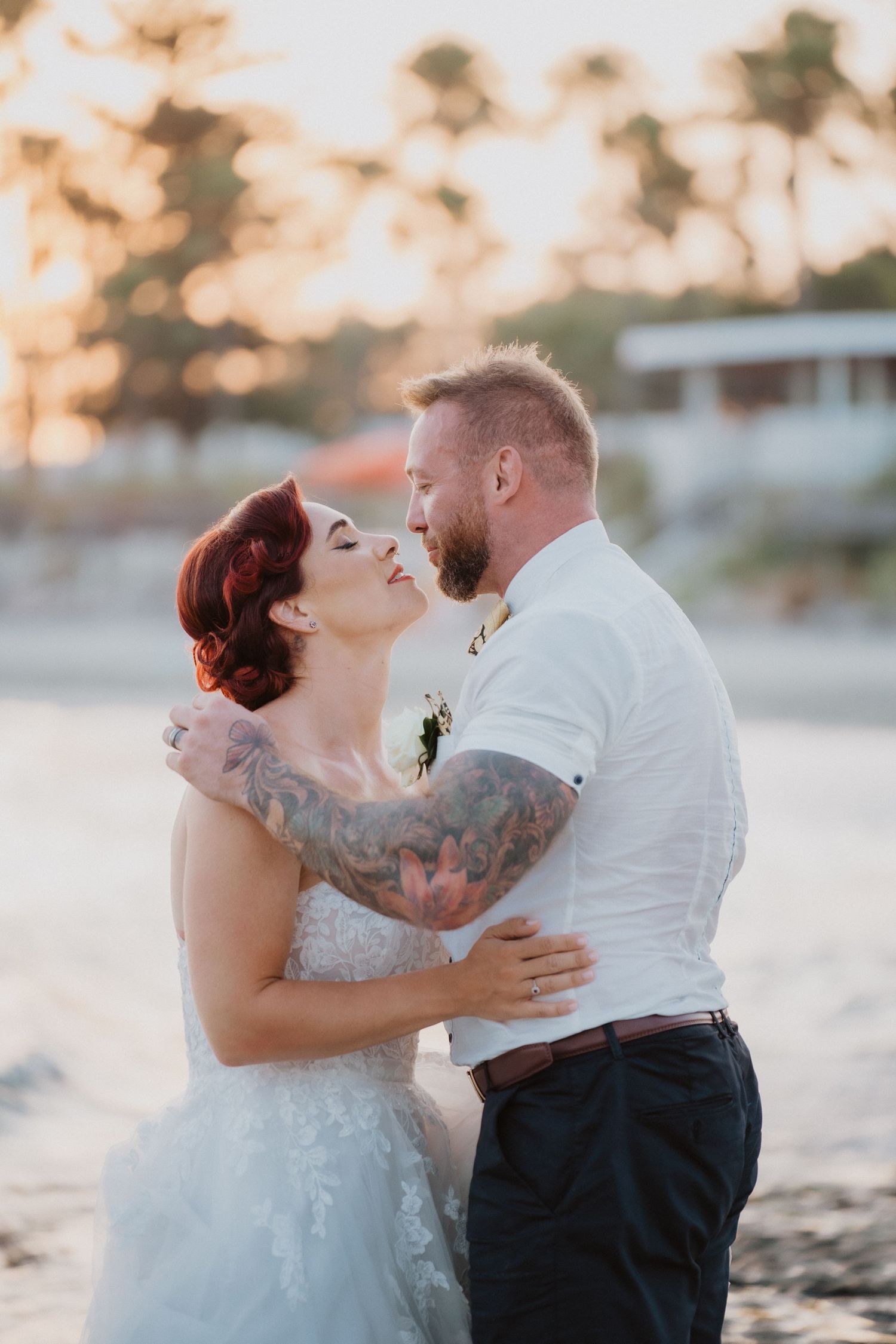 Intimate beach wedding moment at golden hour with palm trees in background.