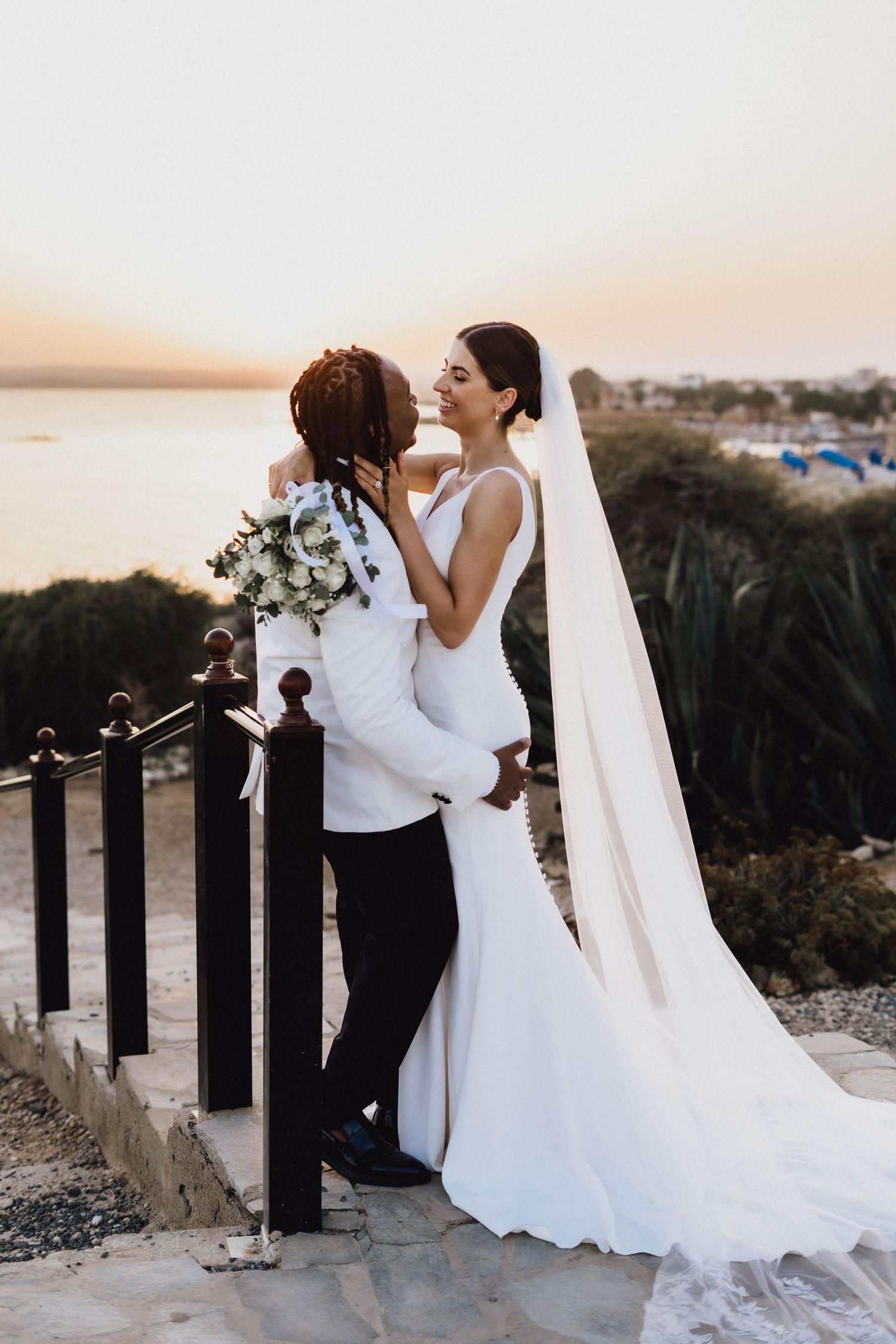 Romantic sunset wedding portrait with coastal views in background.