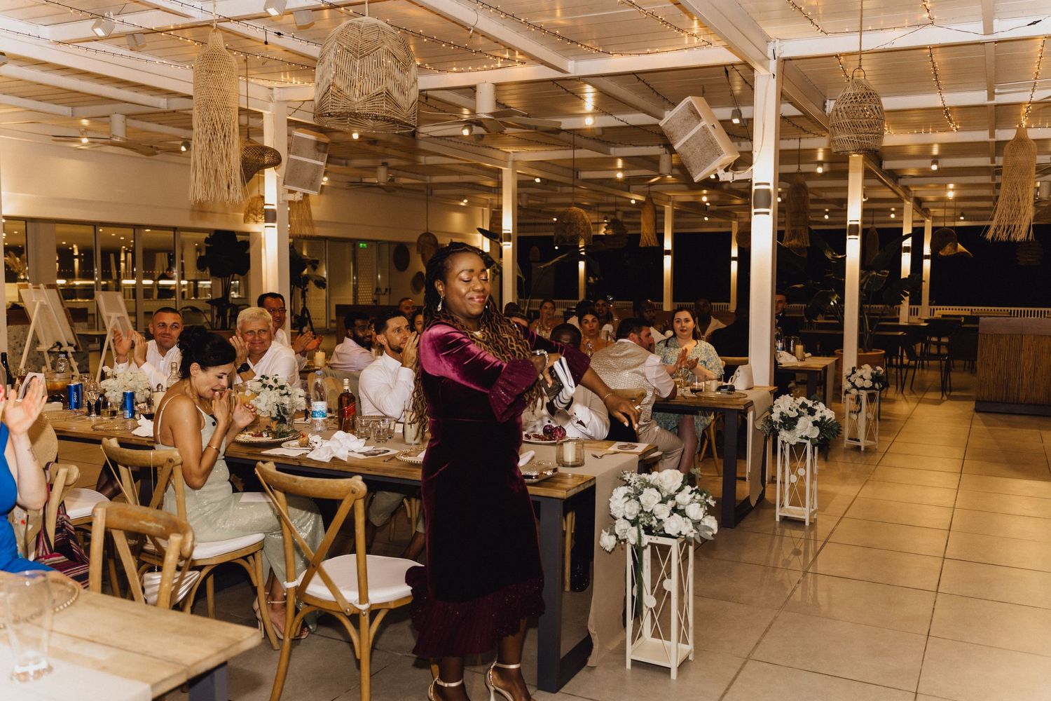 Guests gathered at an elegant indoor wedding reception with rustic decor and string lights.