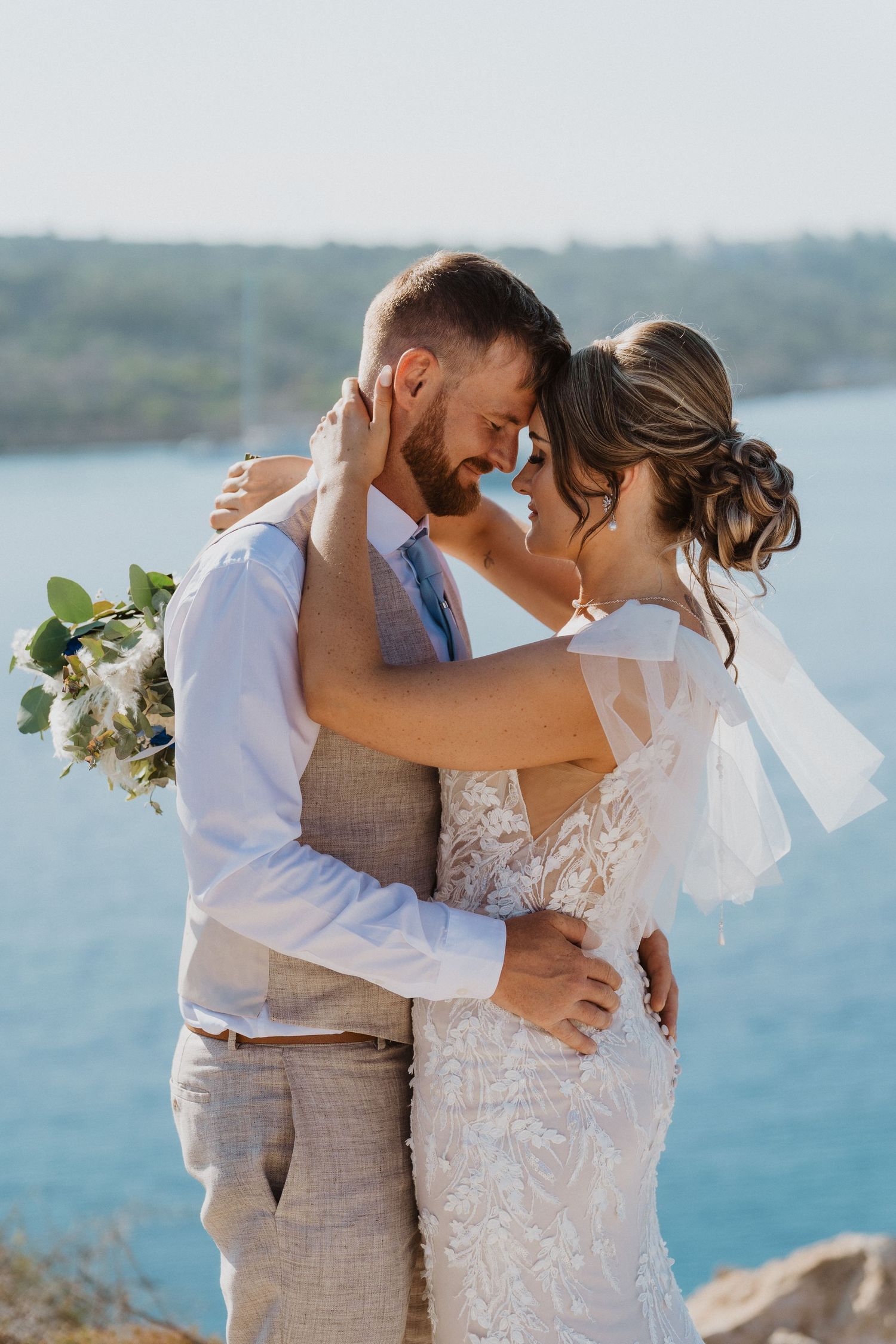 Intimate wedding moment captured against beautiful coastal scenery.