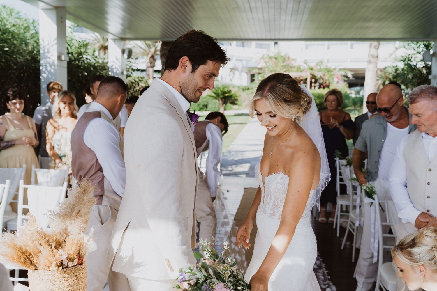 Wedding celebration under a covered pavilion with white decor and natural greenery.
