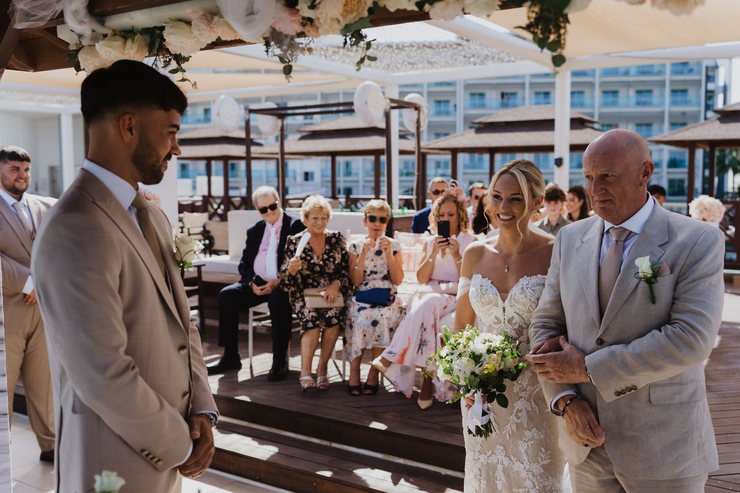 Wedding guests celebrate during an outdoor ceremony with beachfront views.