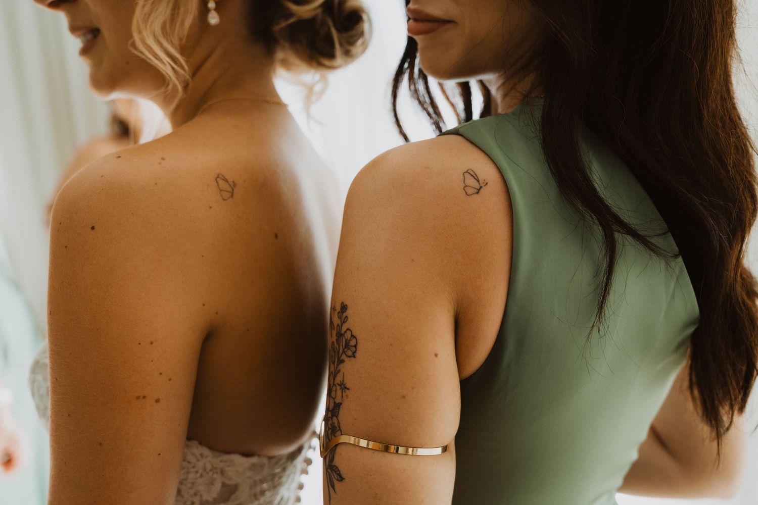 Close-up details of bridesmaids wearing elegant sage green and blush colored dresses.