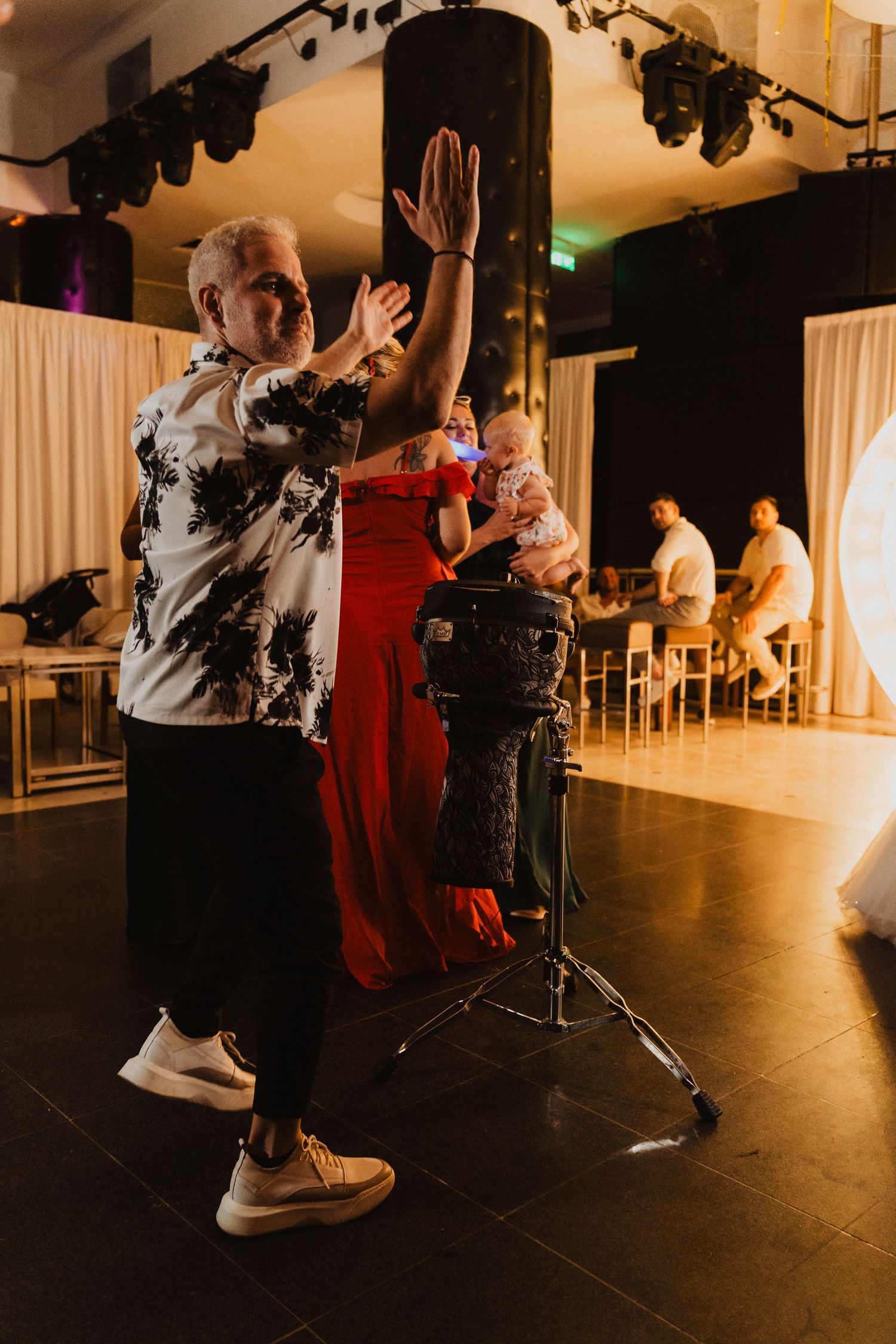 People dancing in a ballroom with black stage lighting and white curtains in the background.