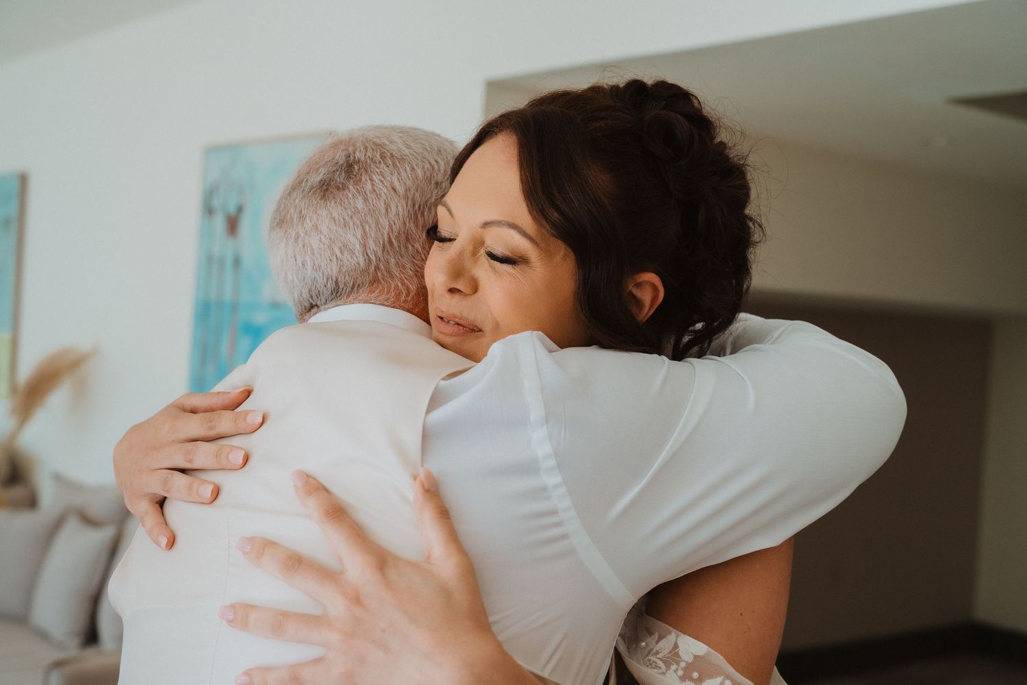 Two people sharing a warm embrace in a softly lit indoor setting, captured in an intimate moment.
