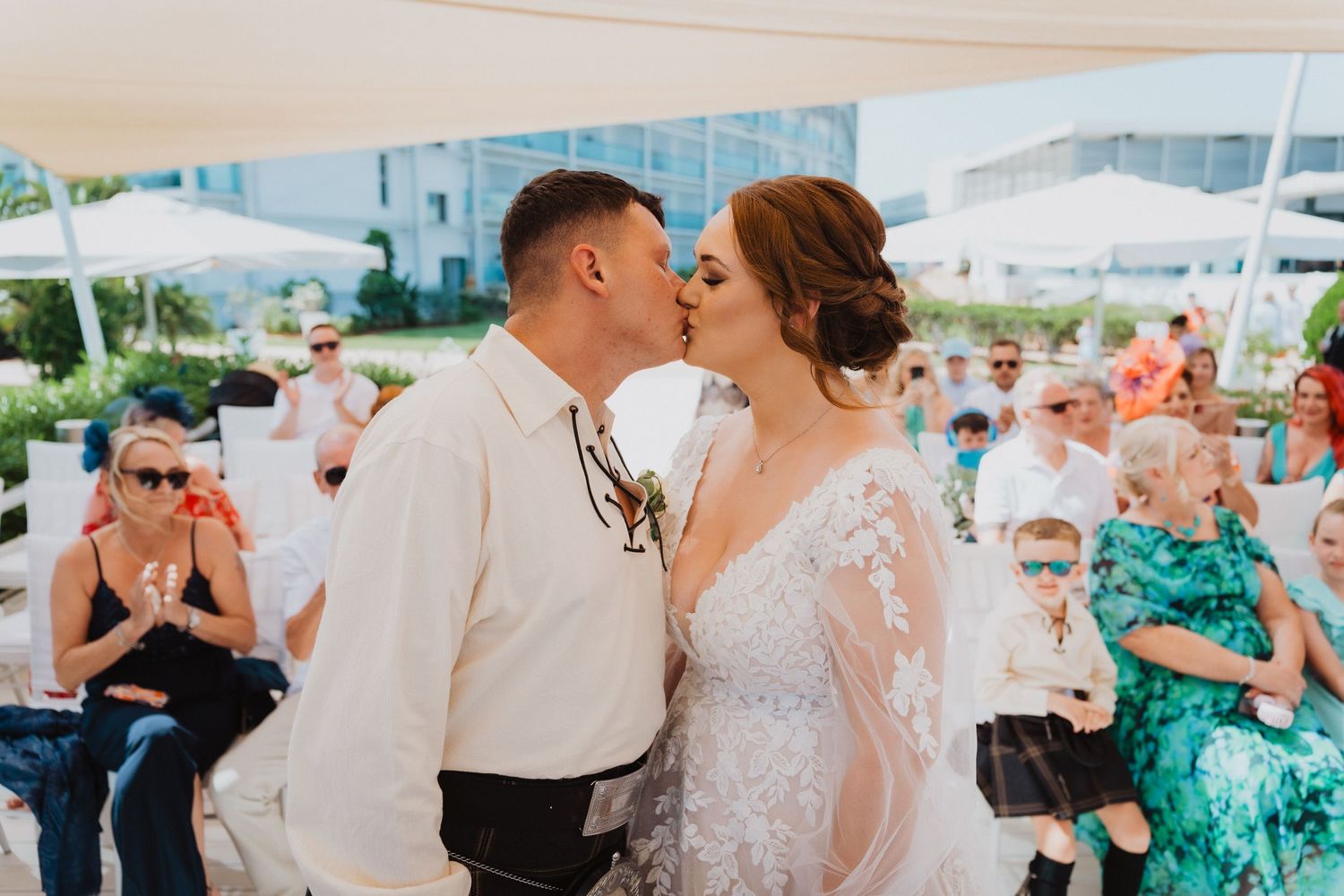 Romantic kiss shared between newlyweds at their outdoor beach wedding ceremony.
