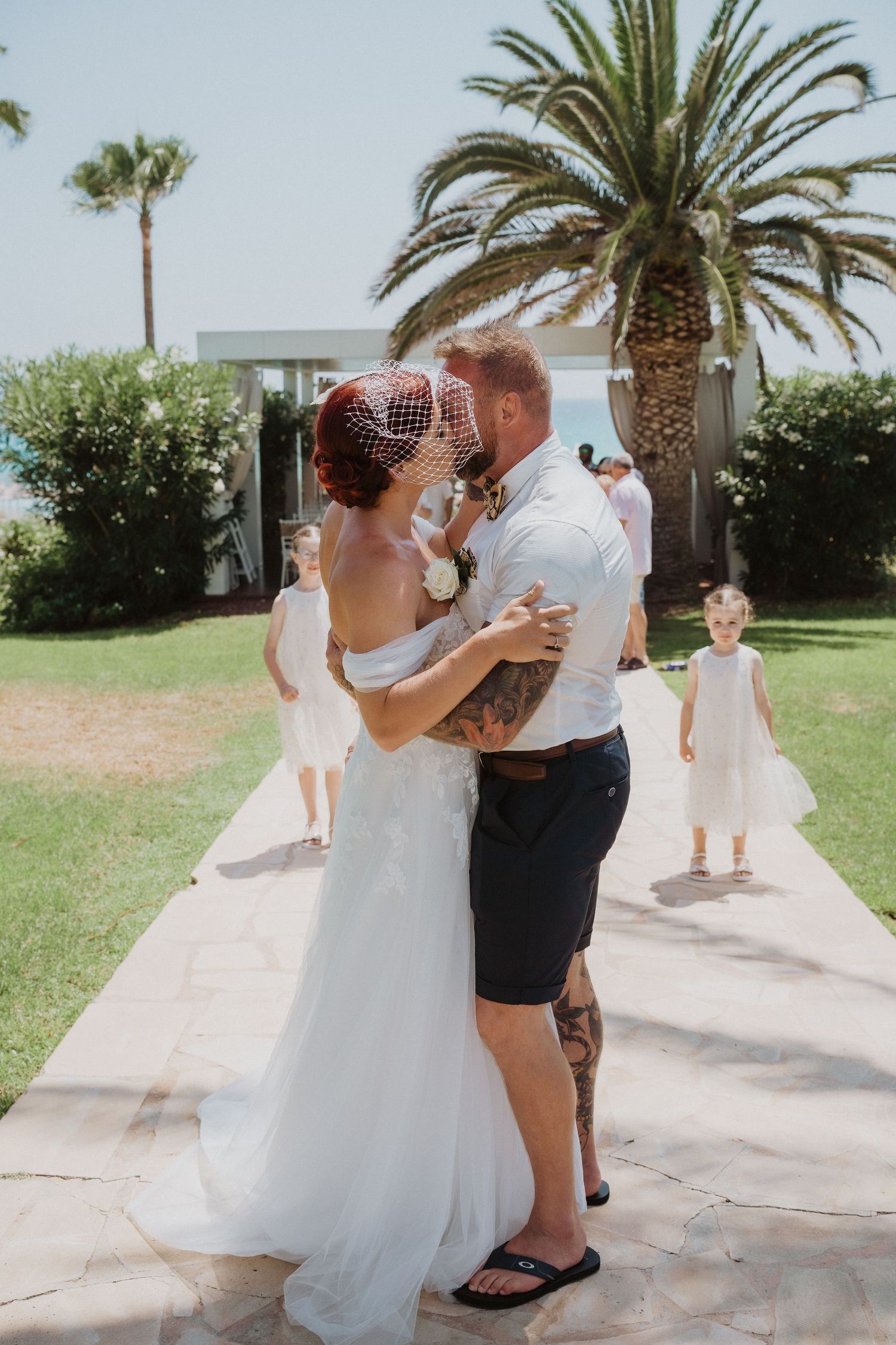 Romantic wedding moment under palm trees at a beachside venue.