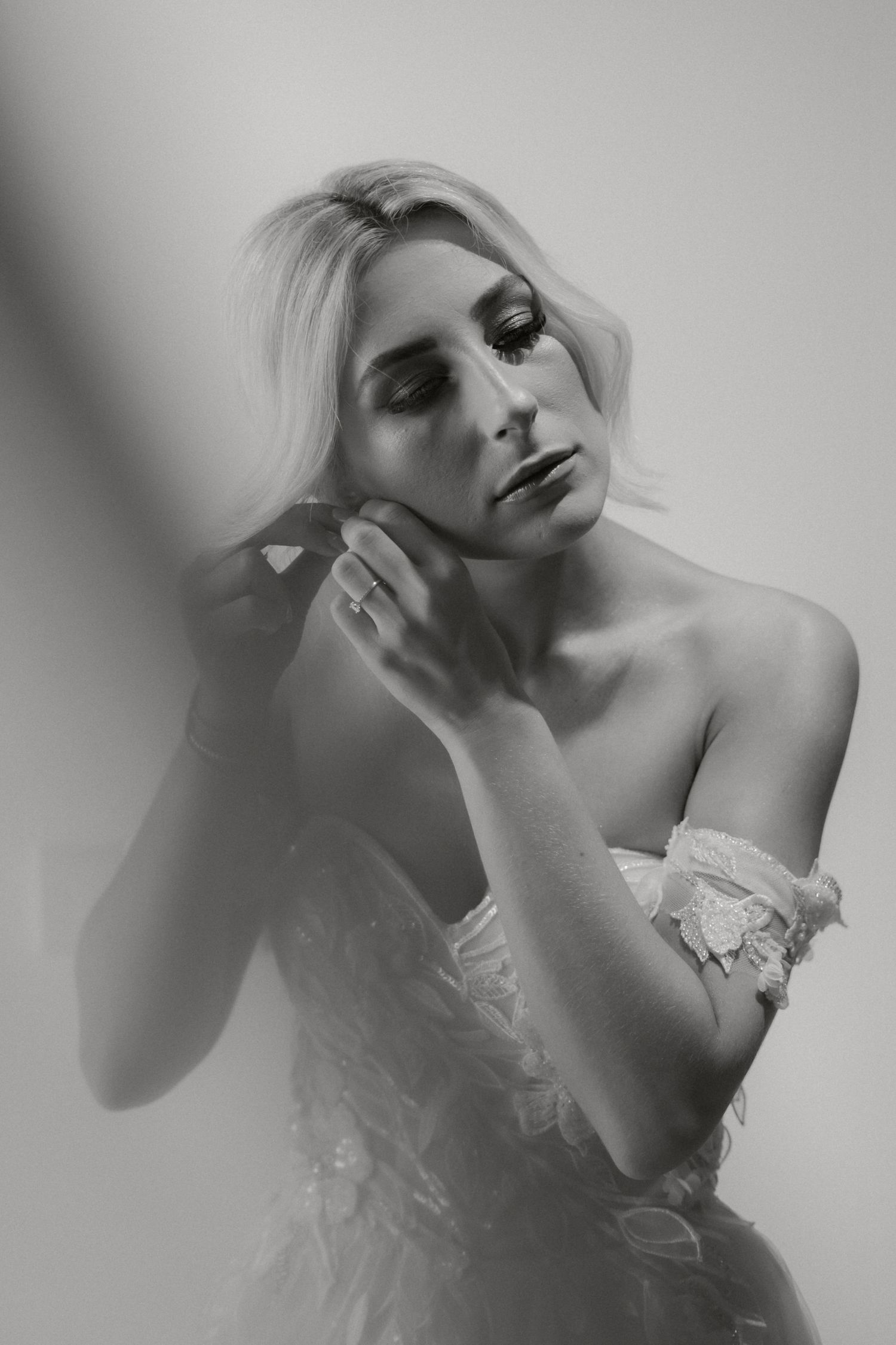 Artistic black and white bridal portrait with dramatic shadows and ethereal posing.