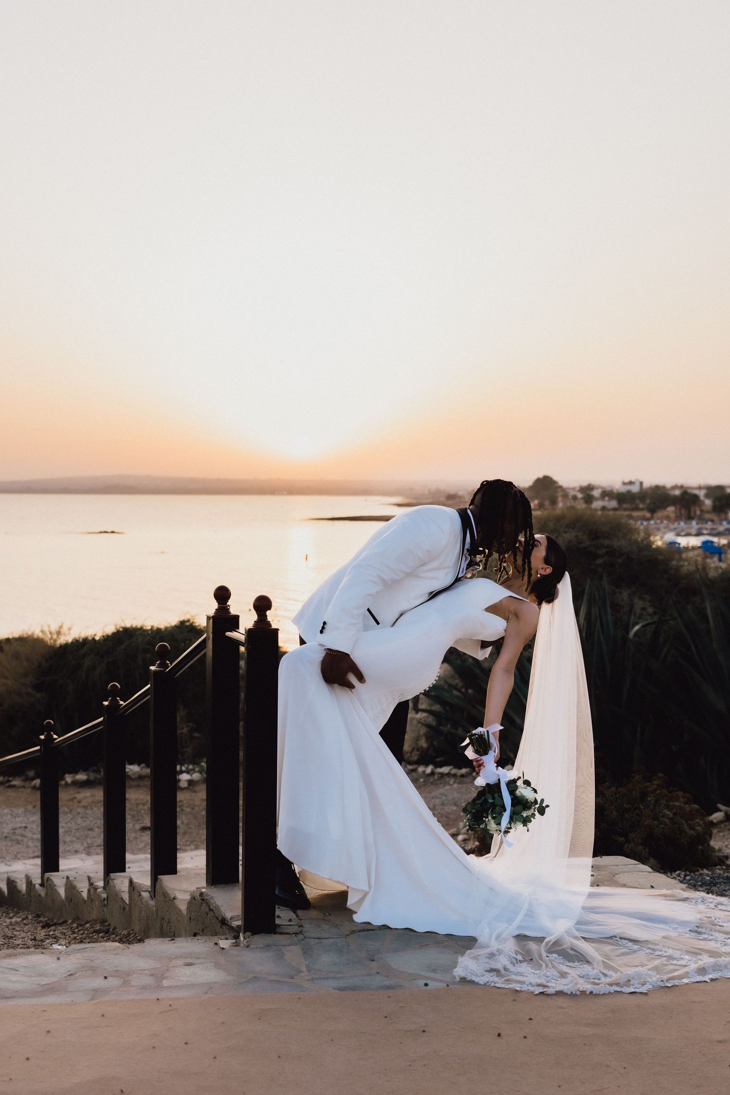 Romantic dip pose during sunset wedding photoshoot by the ocean.