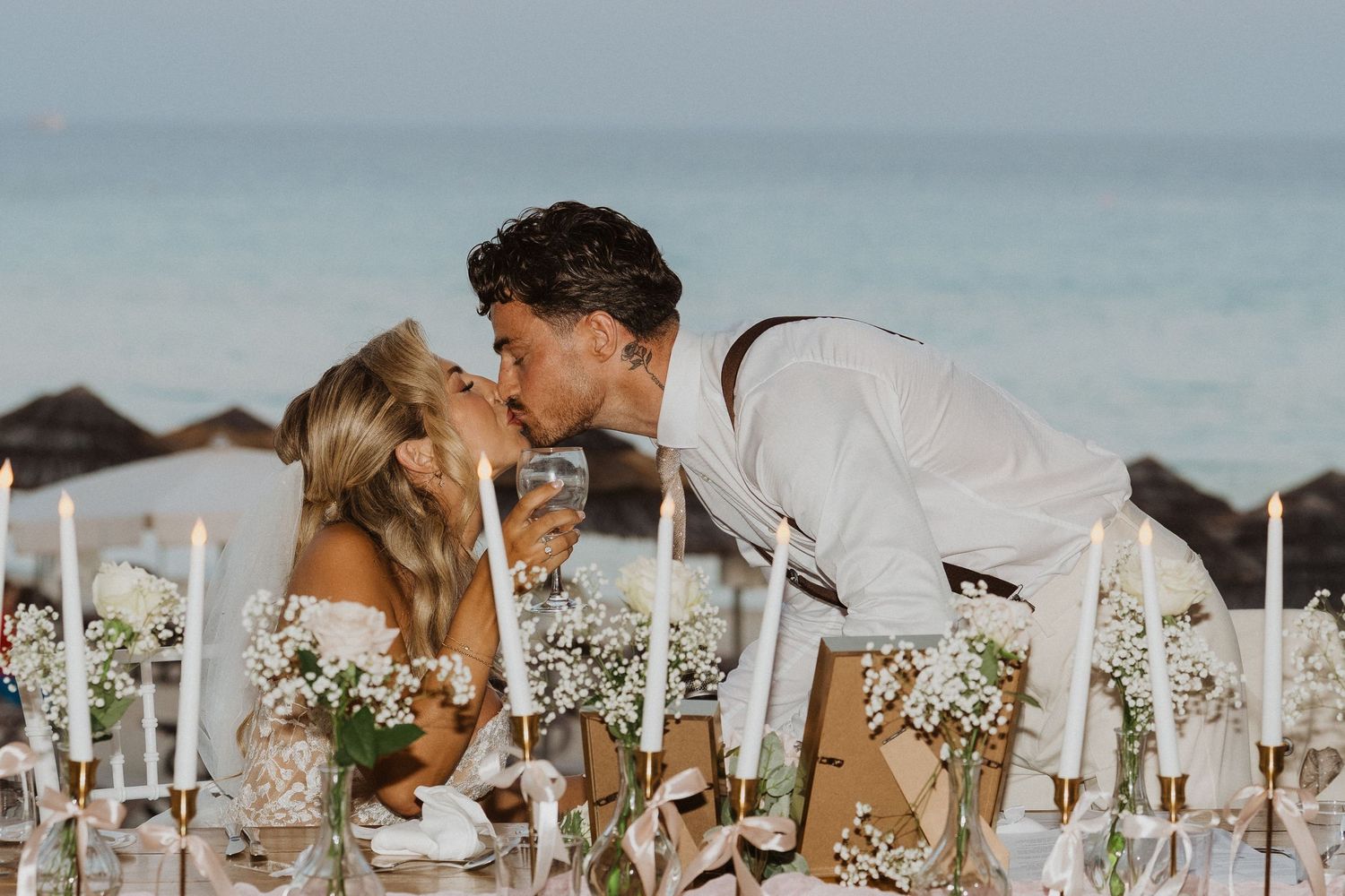 A romantic beach wedding ceremony setup with white chairs and floral arrangements along a sandy shoreline.