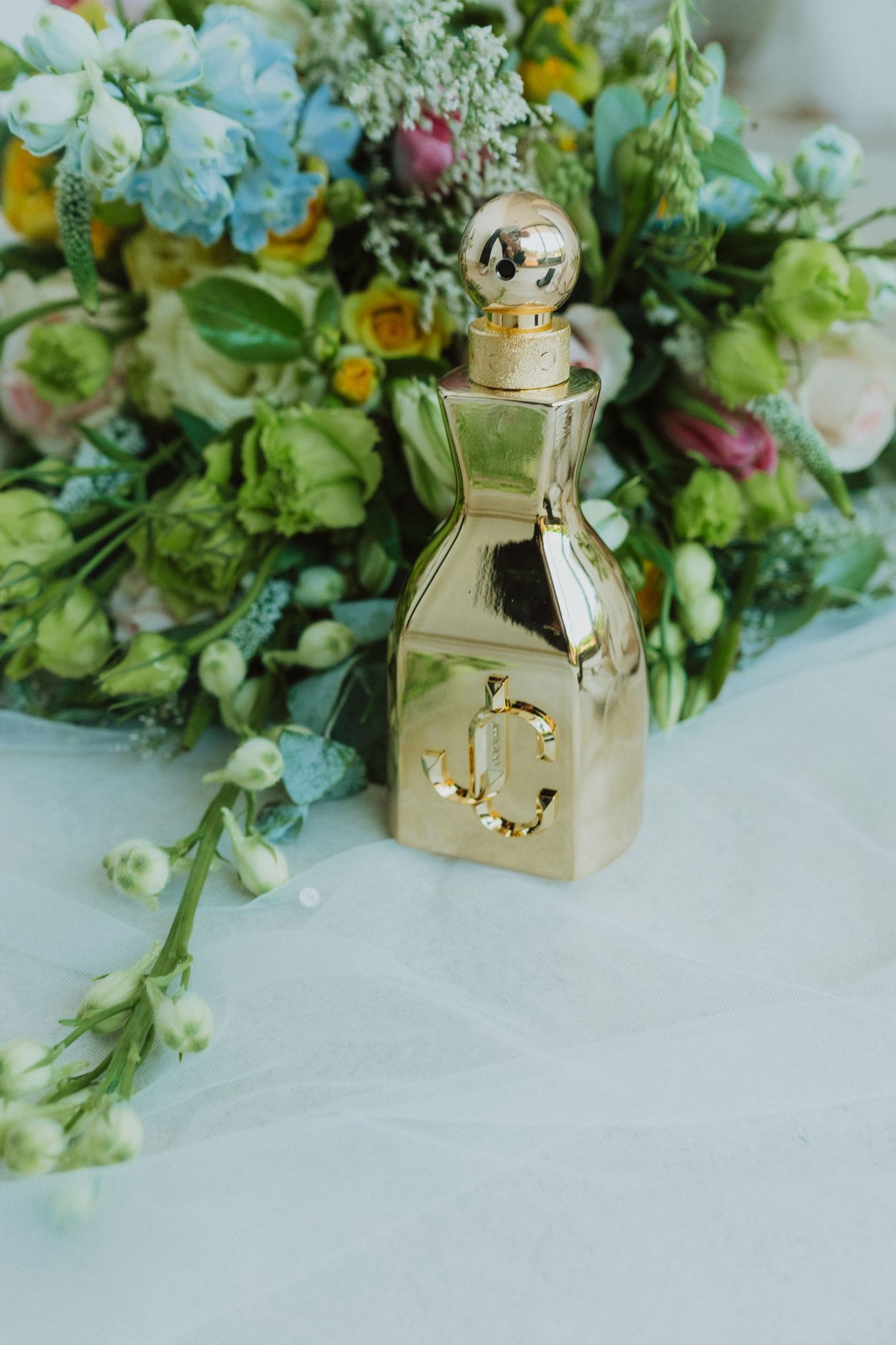Elegant floral arrangements with green and white blooms paired with golden decorative accents on a light surface.