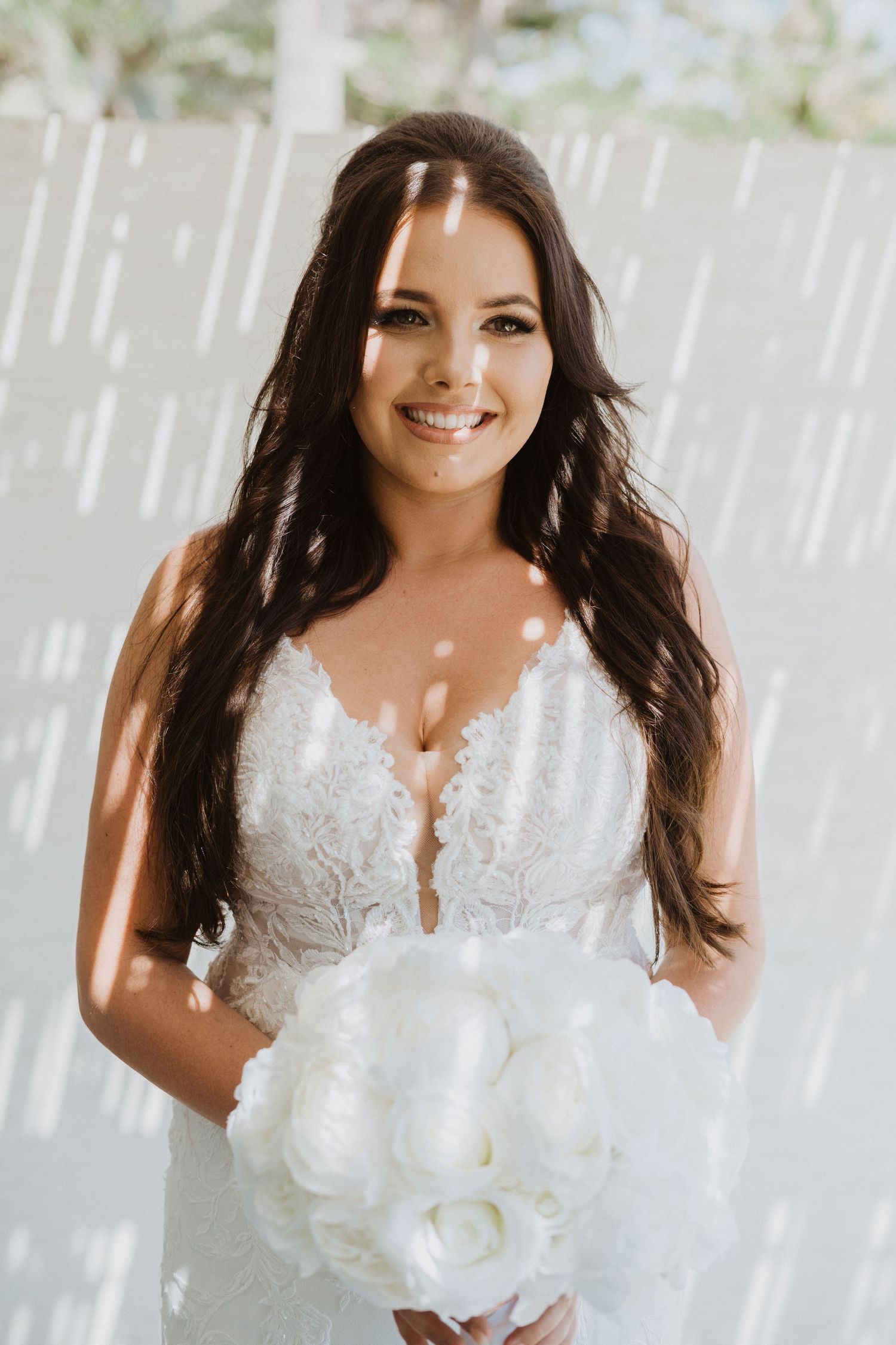 Elegant lace wedding dress details with floral appliques and delicate beading against a white backdrop.