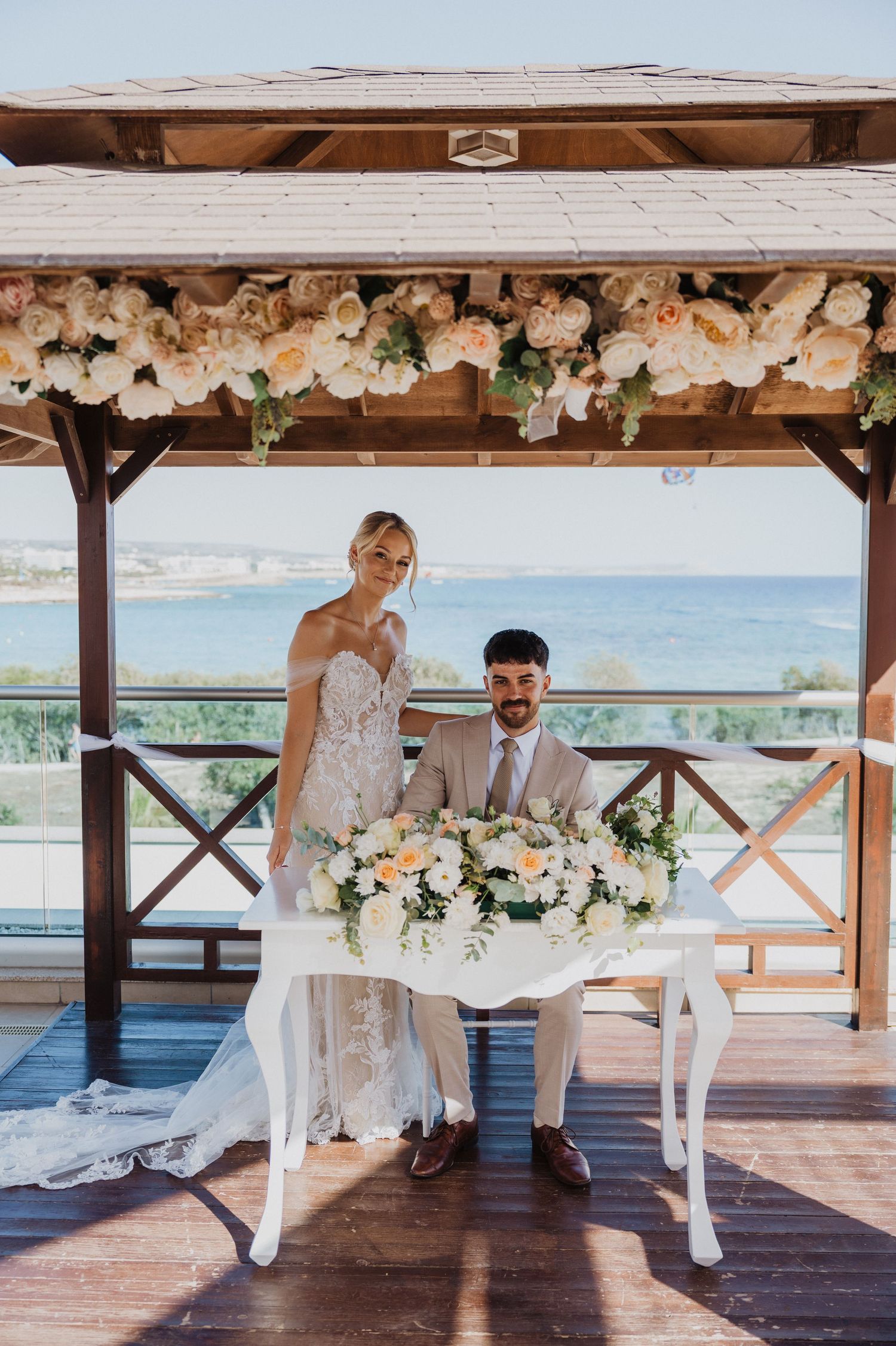 Elegant covered deck wedding venue decorated with white flowers overlooking the ocean.