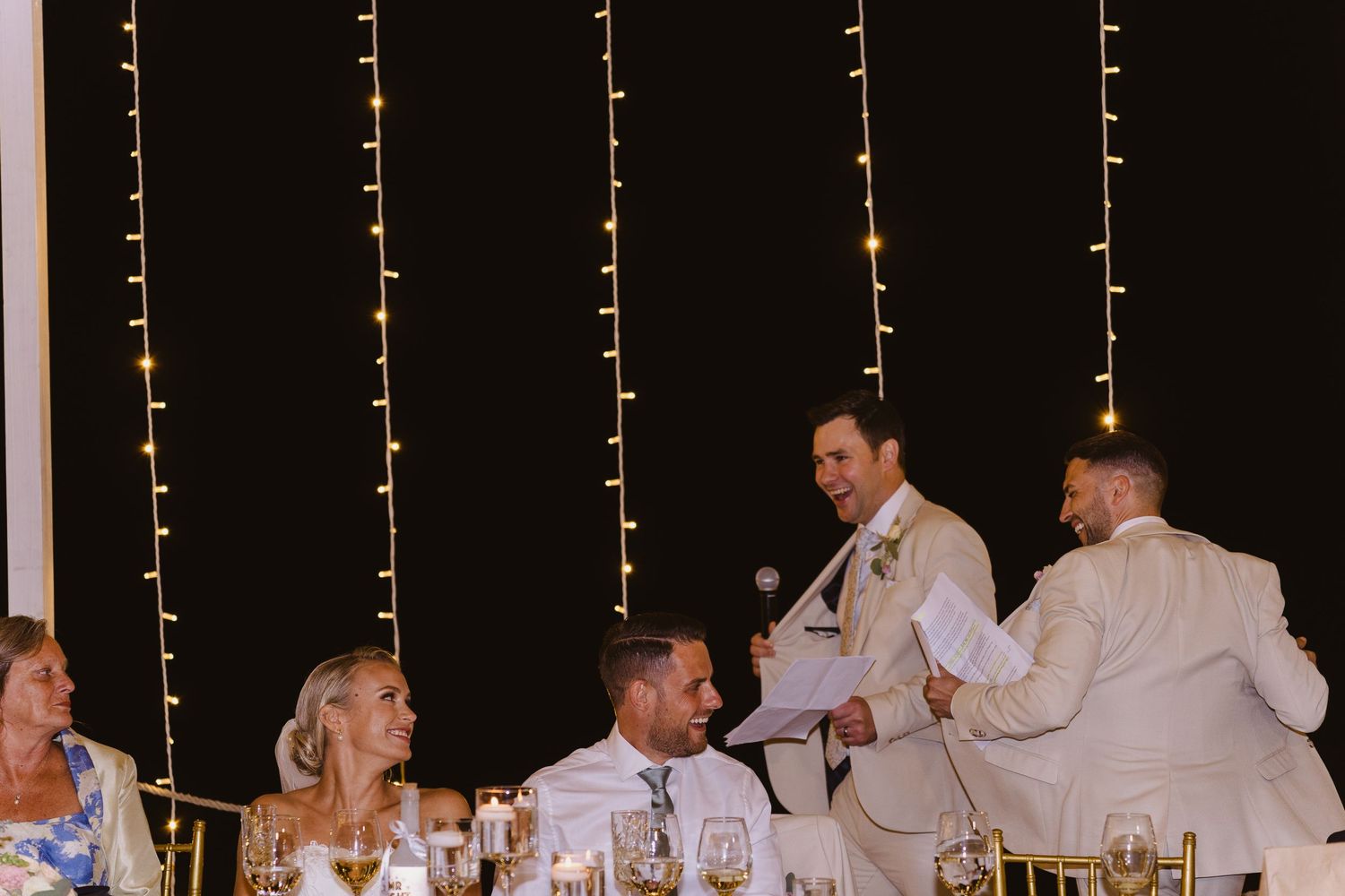 Wedding party sharing laughs during reception toasts and speeches.