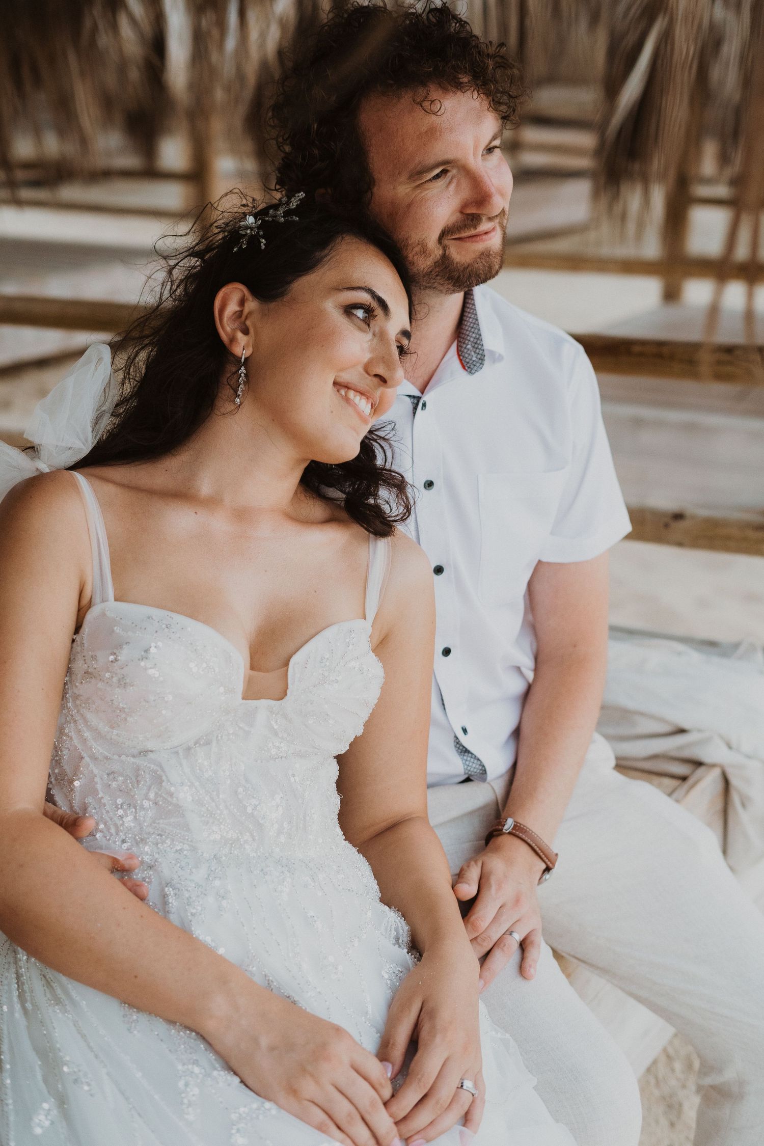 A close-up wedding portrait capturing an intimate moment under a beach palapa.