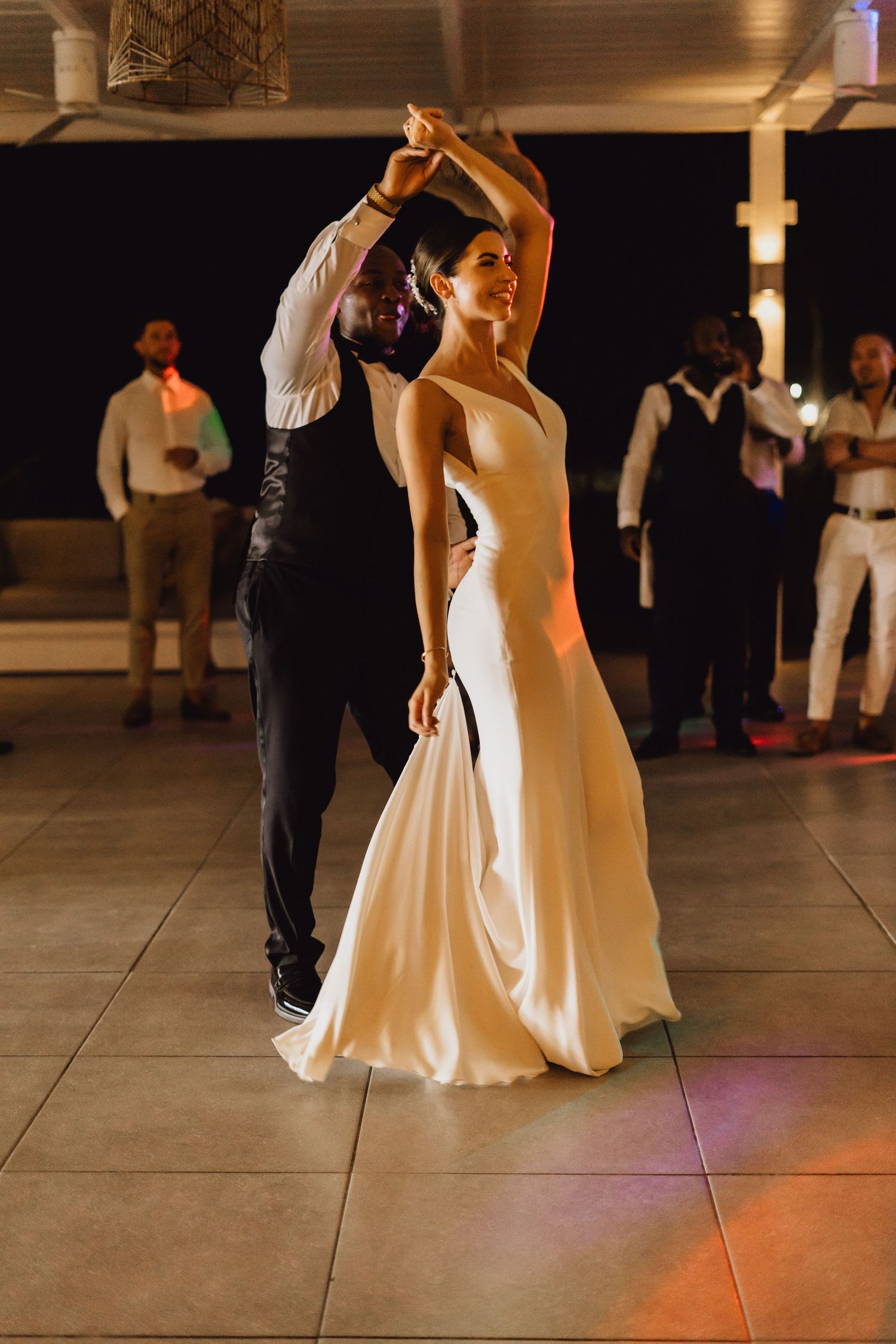A graceful dance twirl showcasing a flowing white wedding gown against dark background.