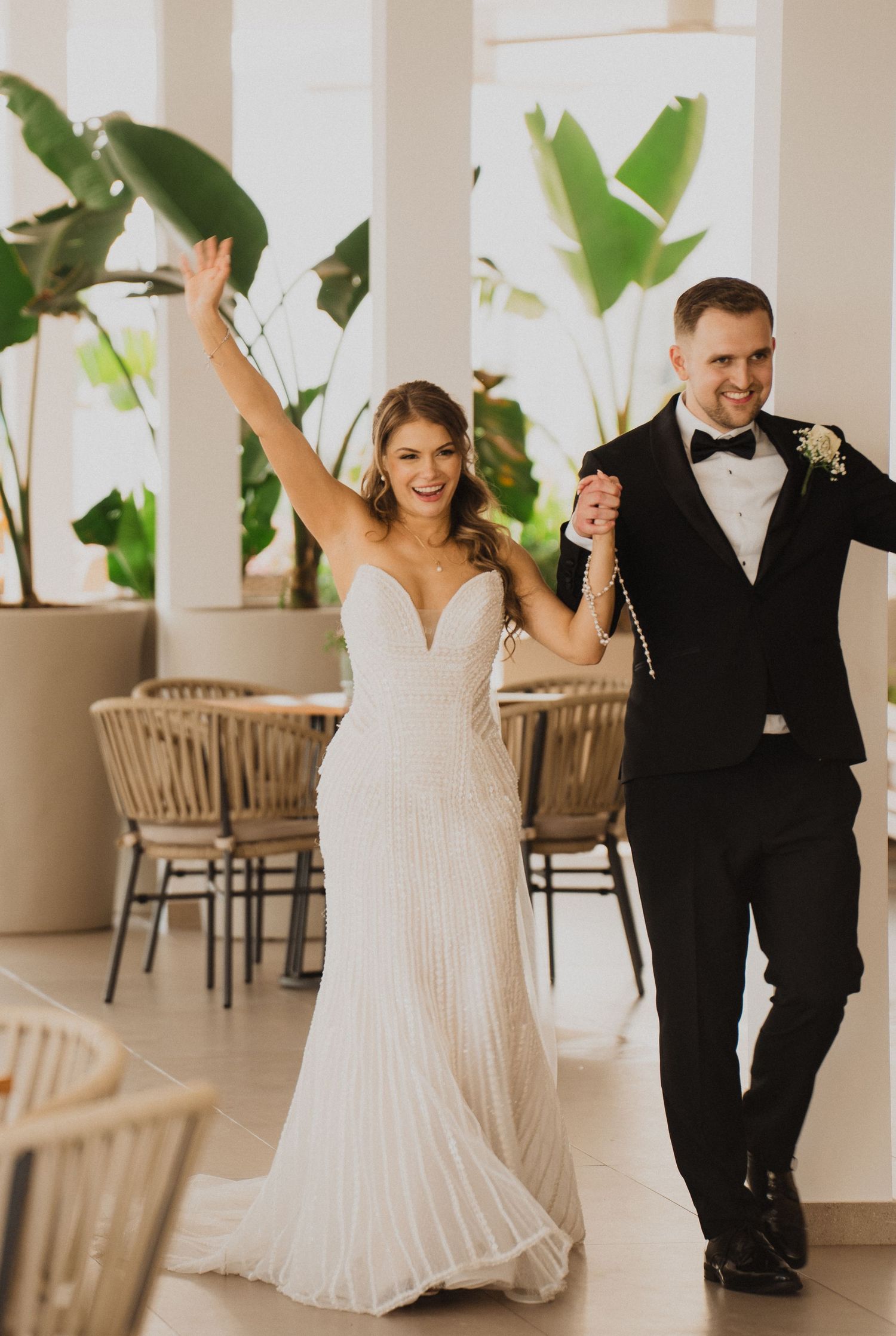 Radiant bride raises arm in celebration as she and groom make grand entrance at wedding reception.