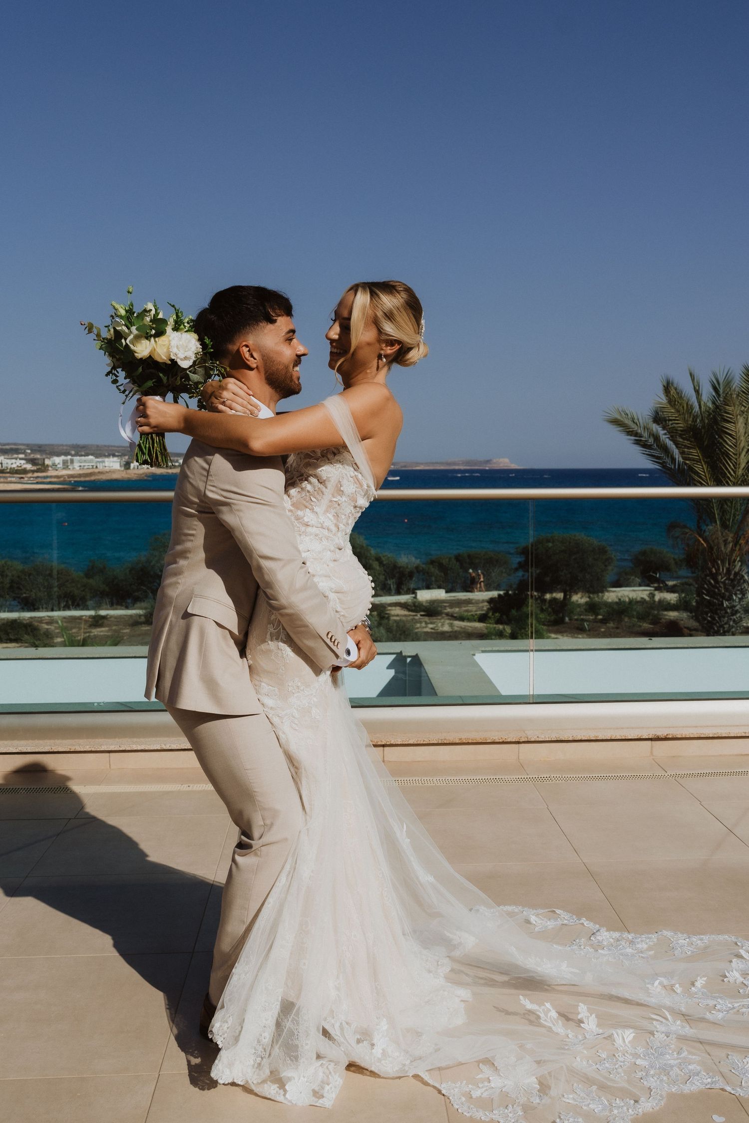 Joyful wedding couple dancing and twirling on a beachfront terrace.