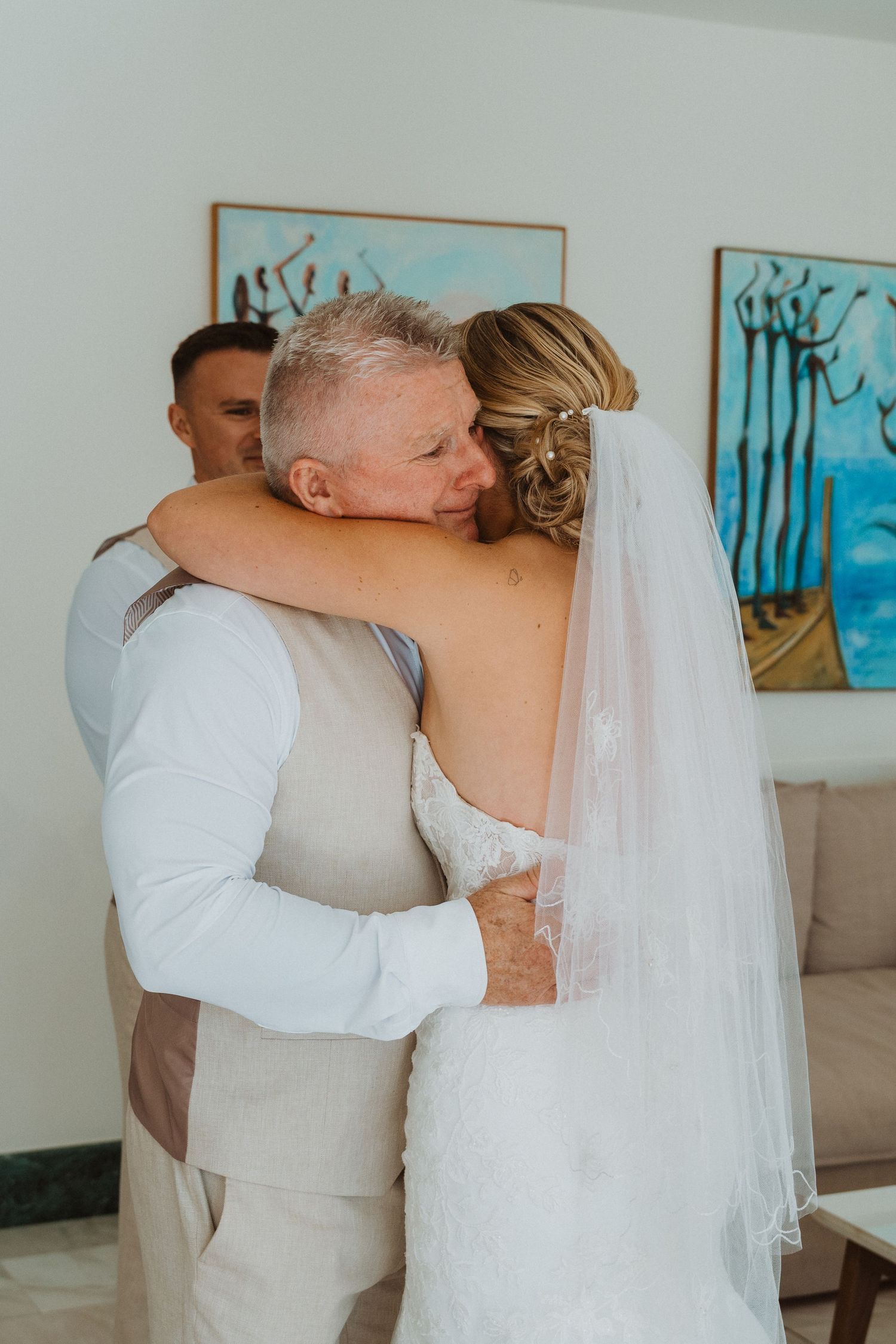 Emotional first look moment between wedding party members in a light-filled room.