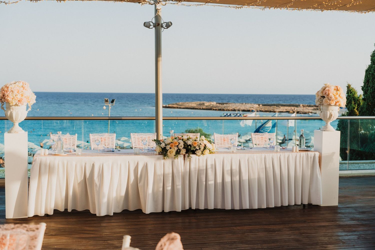 Outdoor wedding reception venue with white draping and ocean view in the background.