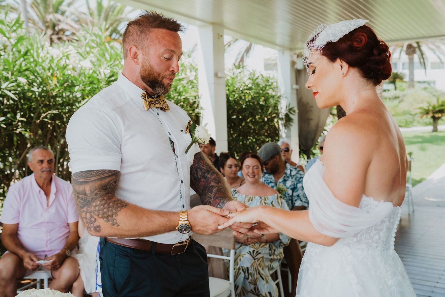 Outdoor wedding ceremony with close-up of ring exchange moment.