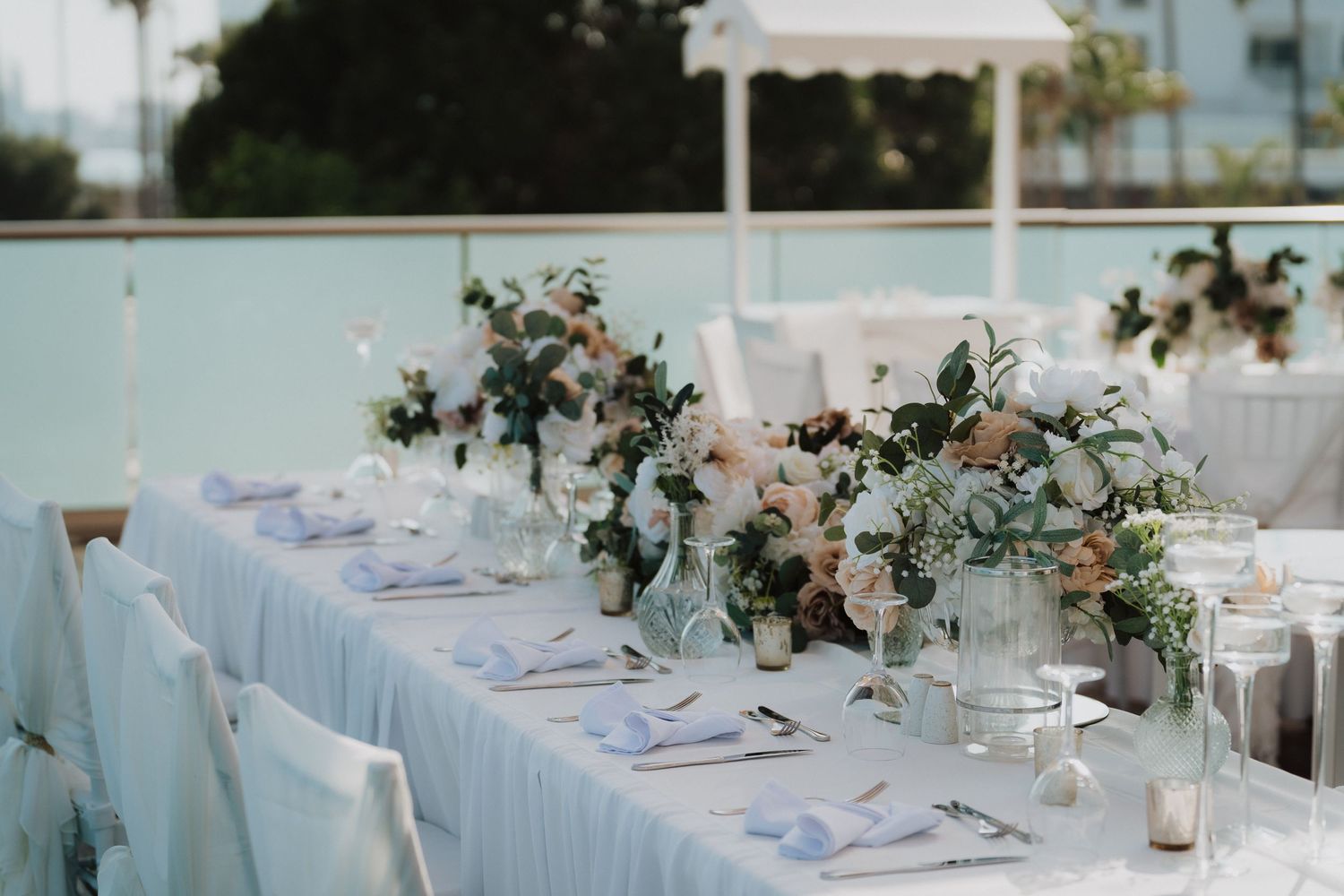 Elegant wedding table setting with soft floral centerpieces and blue linens.