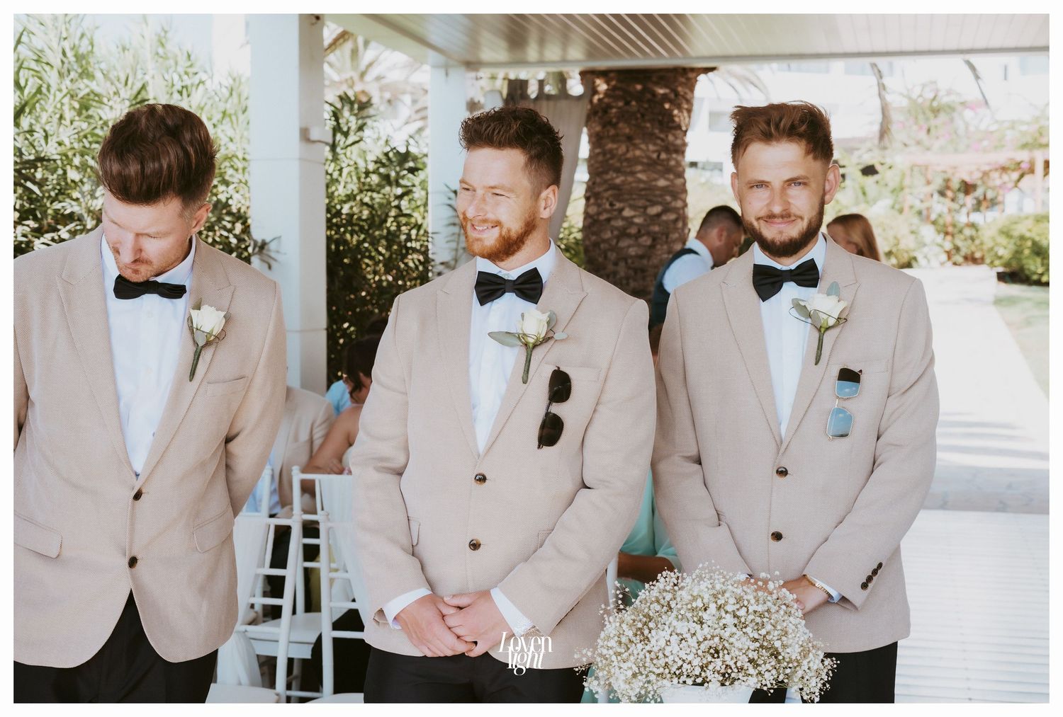 Groomsmen in tan suits and bow ties waiting at the wedding altar.