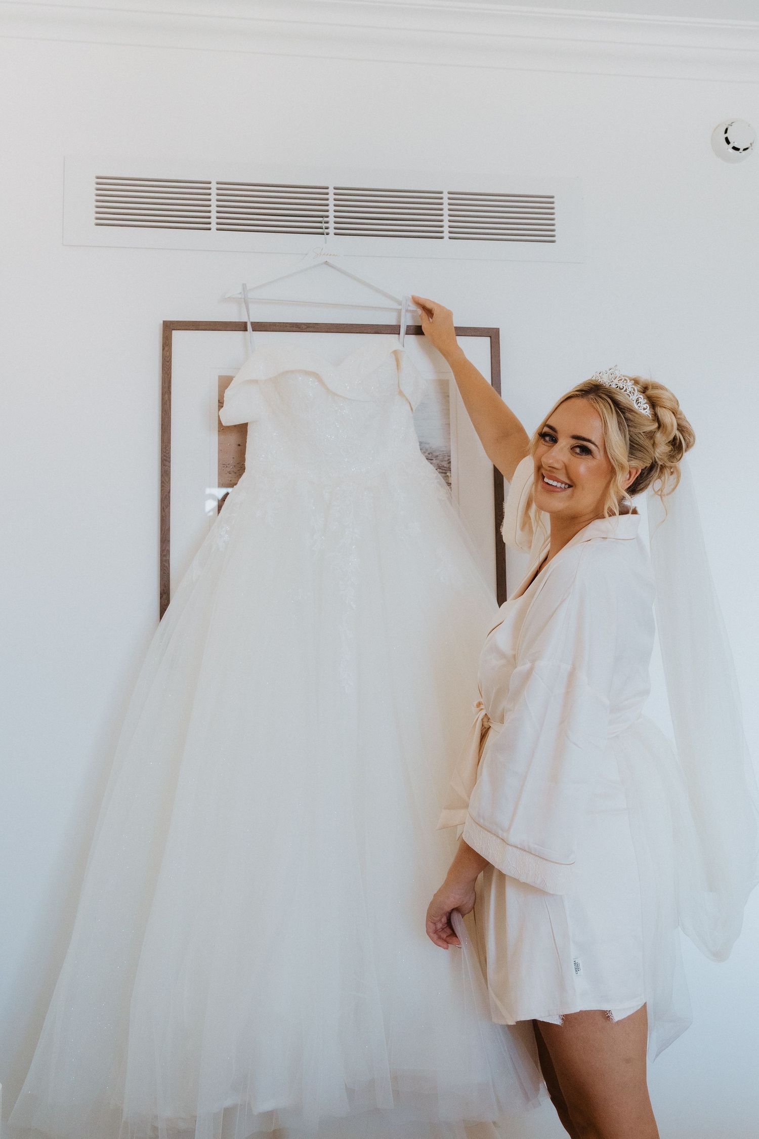 Wedding dress hanging on display in a bright white room.