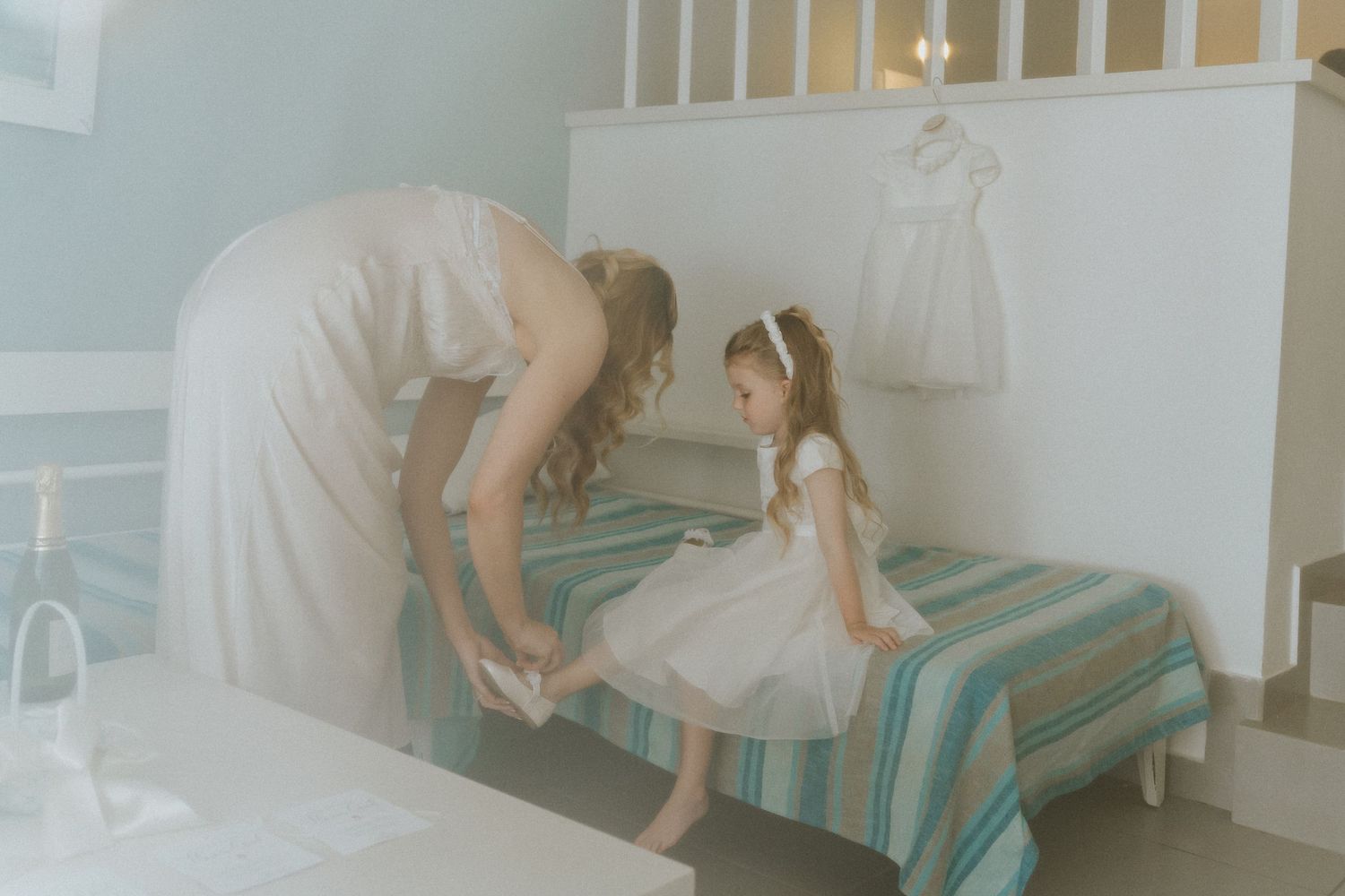 Getting ready moment in a bedroom with striped bedding and white decor.