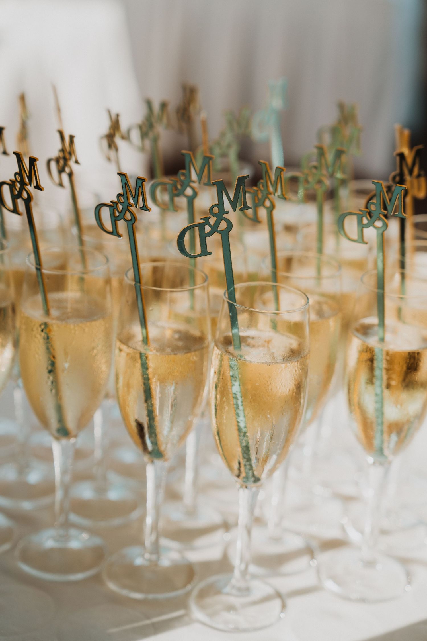 Elegant champagne flutes filled with sparkling wine and decorated with Mr. and Mrs. monogram stirrers at a wedding reception.