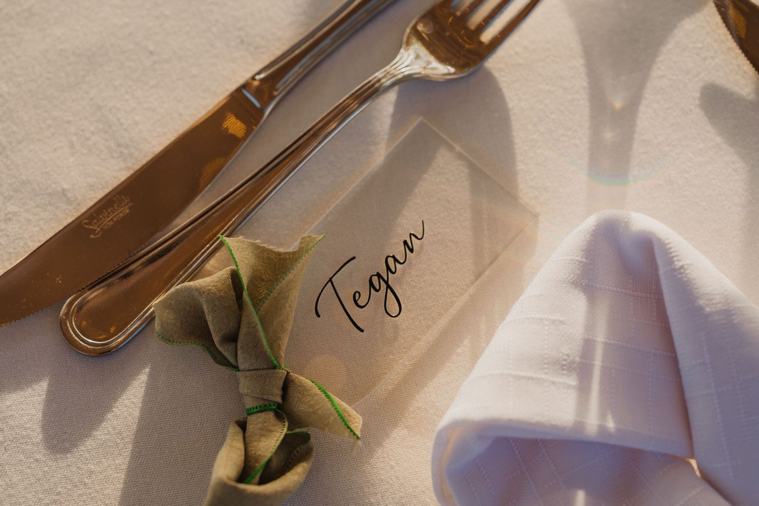 Close-up of wedding place setting with silverware and name card.