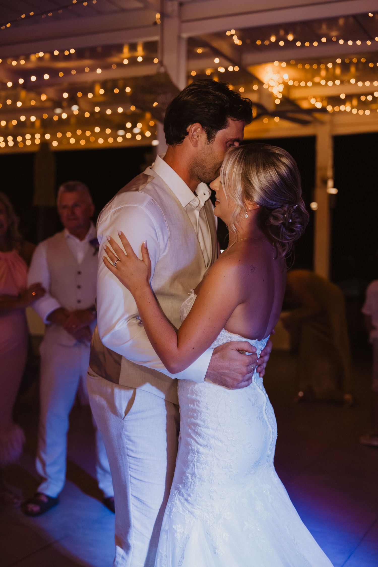 A romantic first dance moment under string lights at an elegant wedding reception.