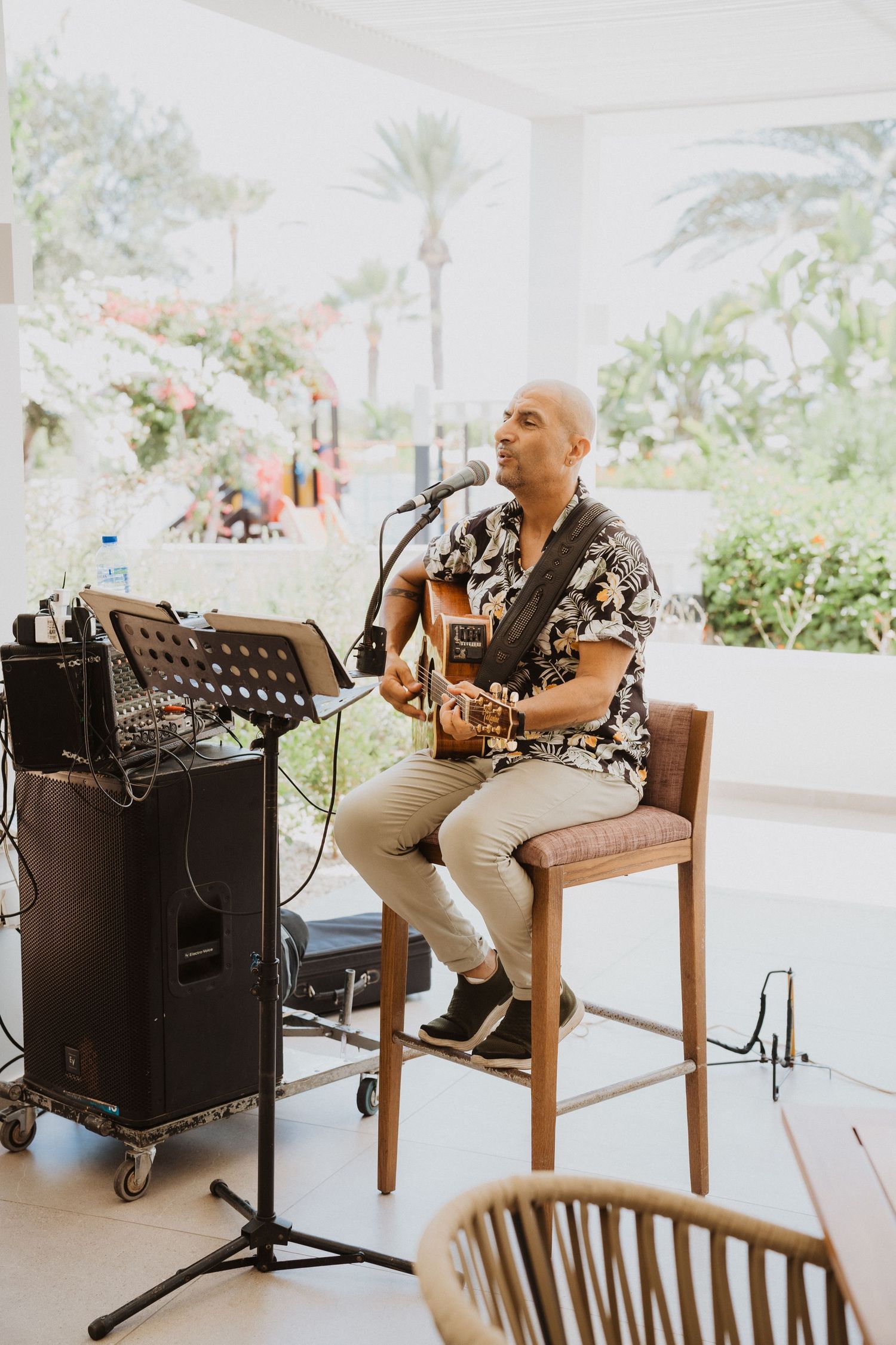 Musician performing with an acoustic guitar and microphone at an outdoor venue.